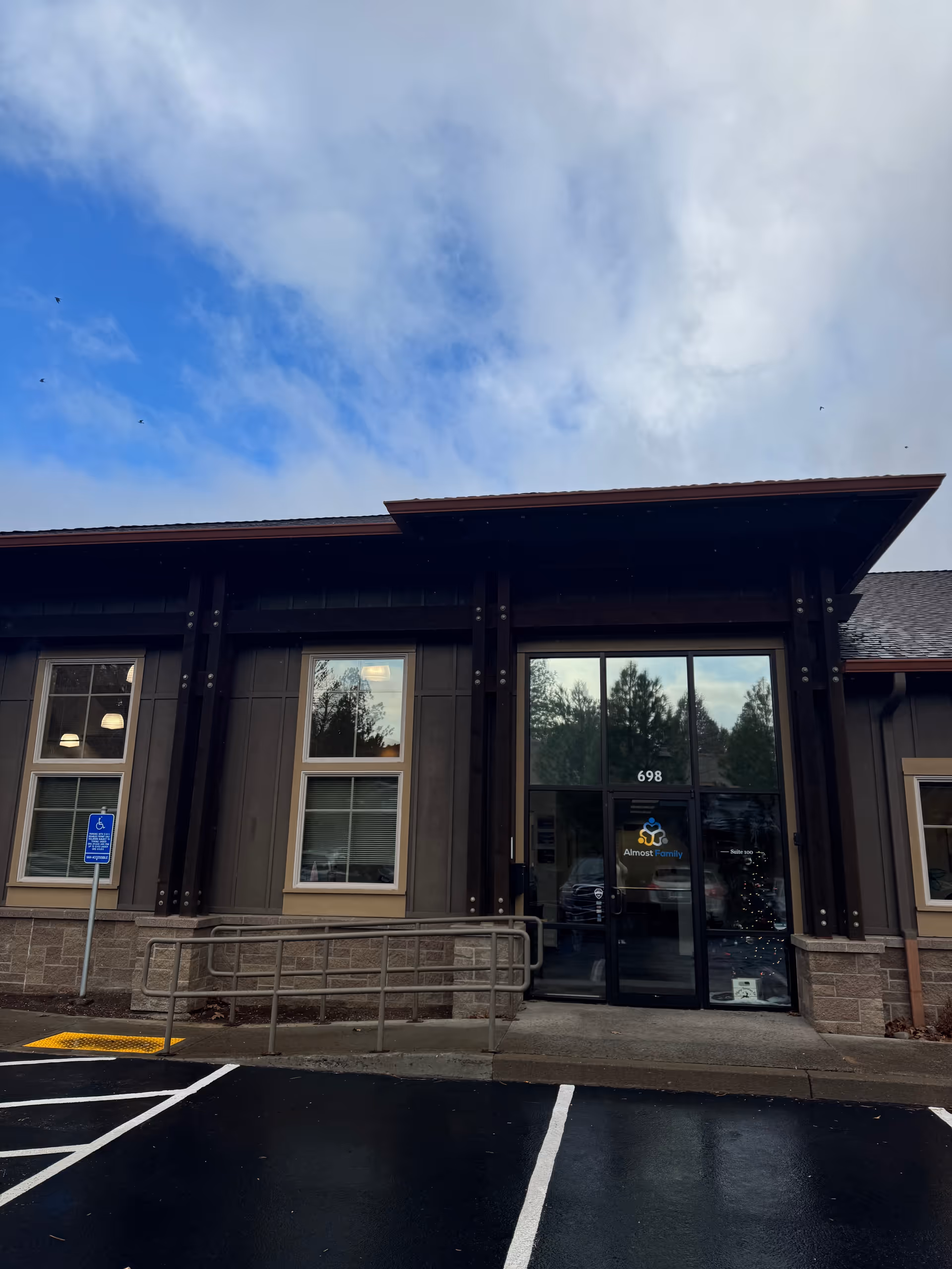Front exterior of Almost Family facility with glass doors and accessible ramp.