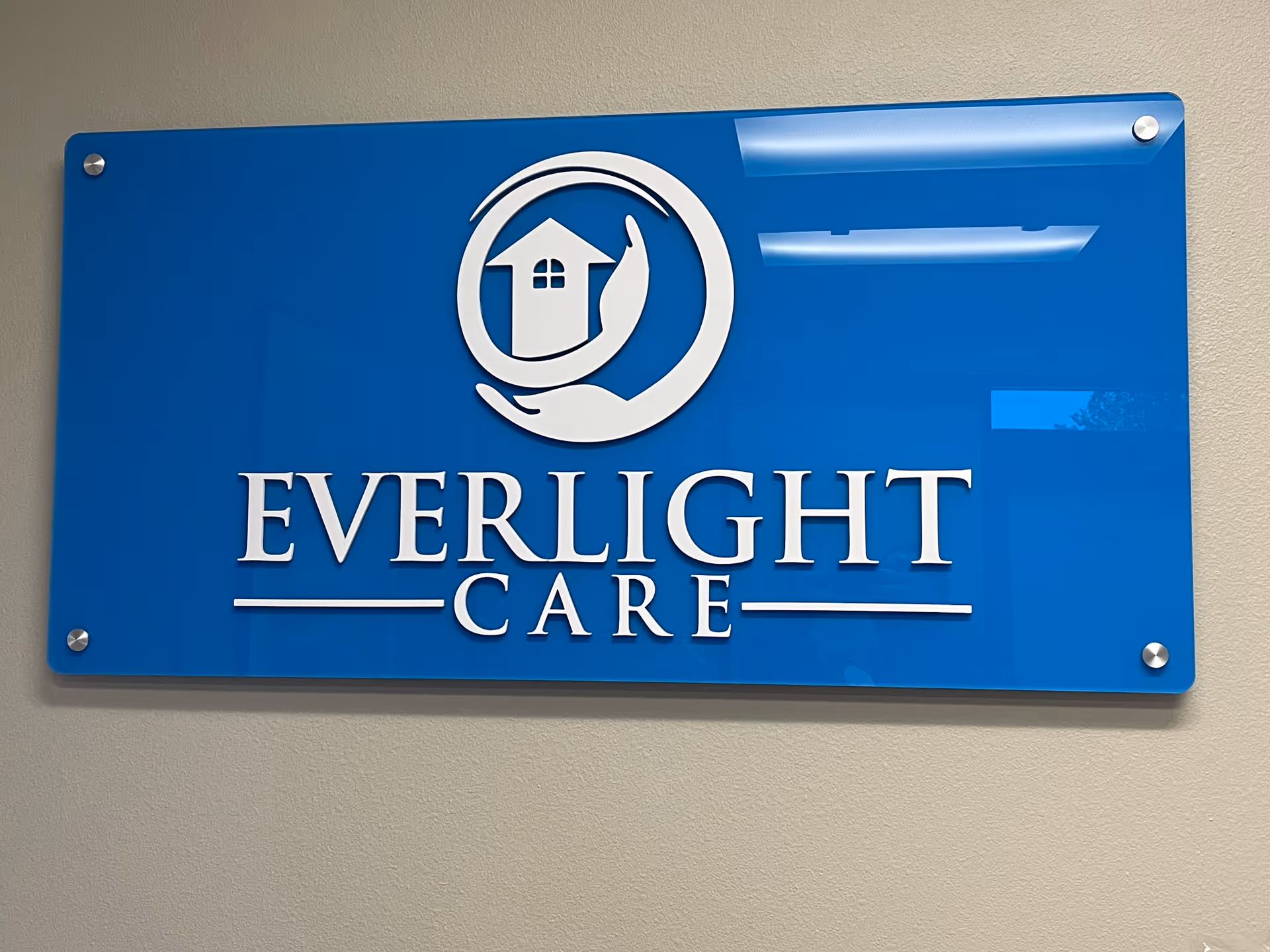 Blue Everlight Care sign with logo mounted on beige interior wall.