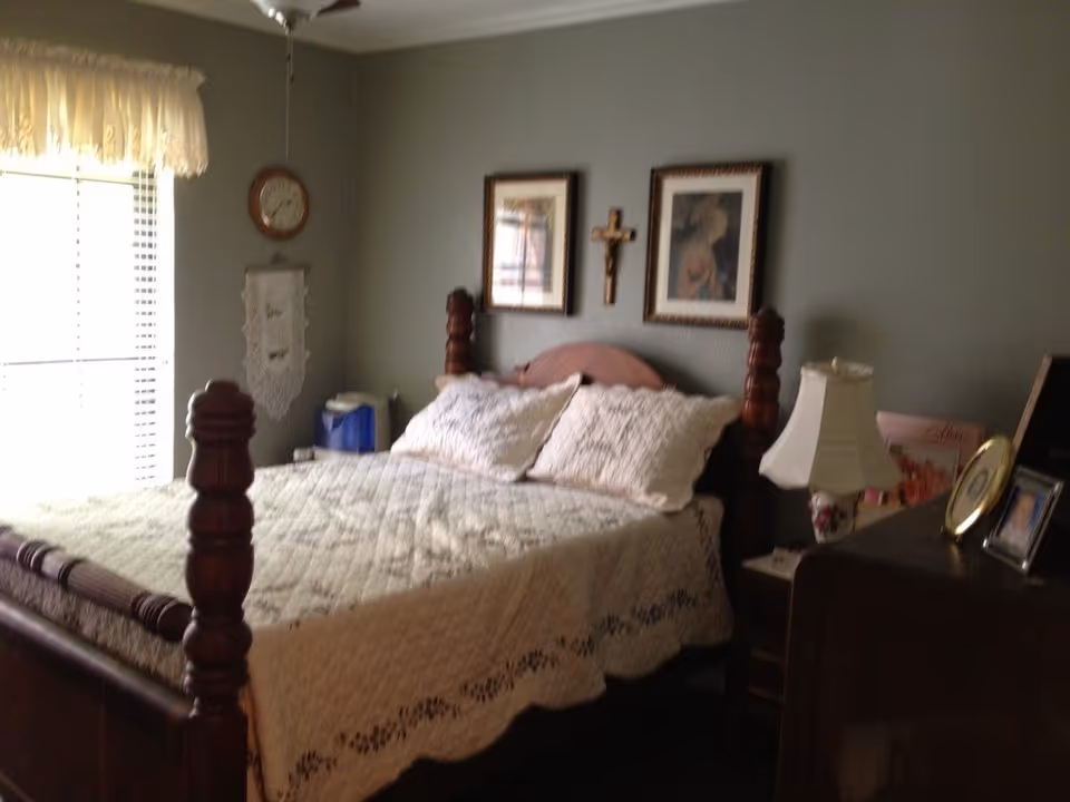 A traditional bedroom with a four-poster bed, dresser, and wall decor.