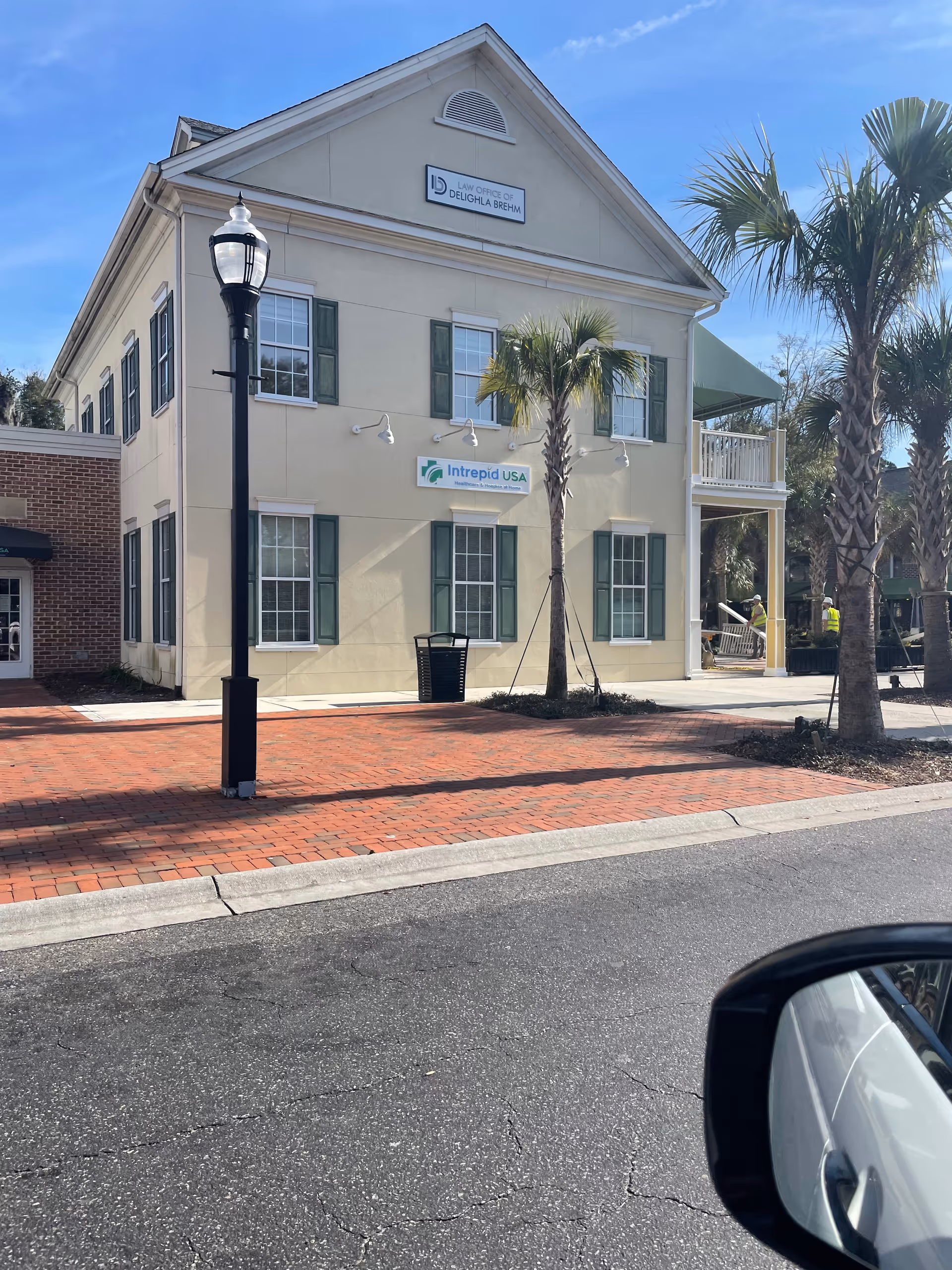 Two-story beige building with green shutters and palm trees, labeled Intrepid USA Home Health.
