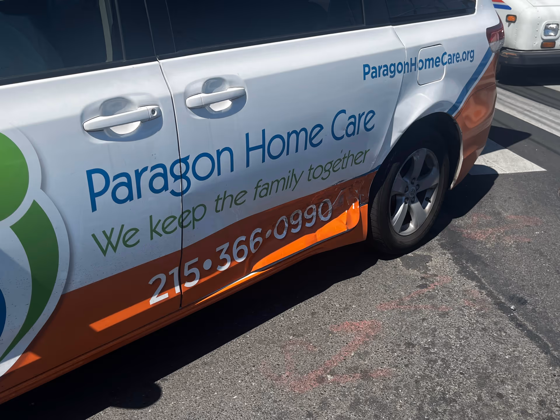Side view of a Paragon Home Care van with branding and phone number.
