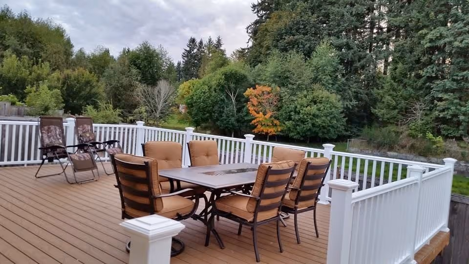 Outdoor deck with table, cushioned chairs, and loungers overlooking greenery.