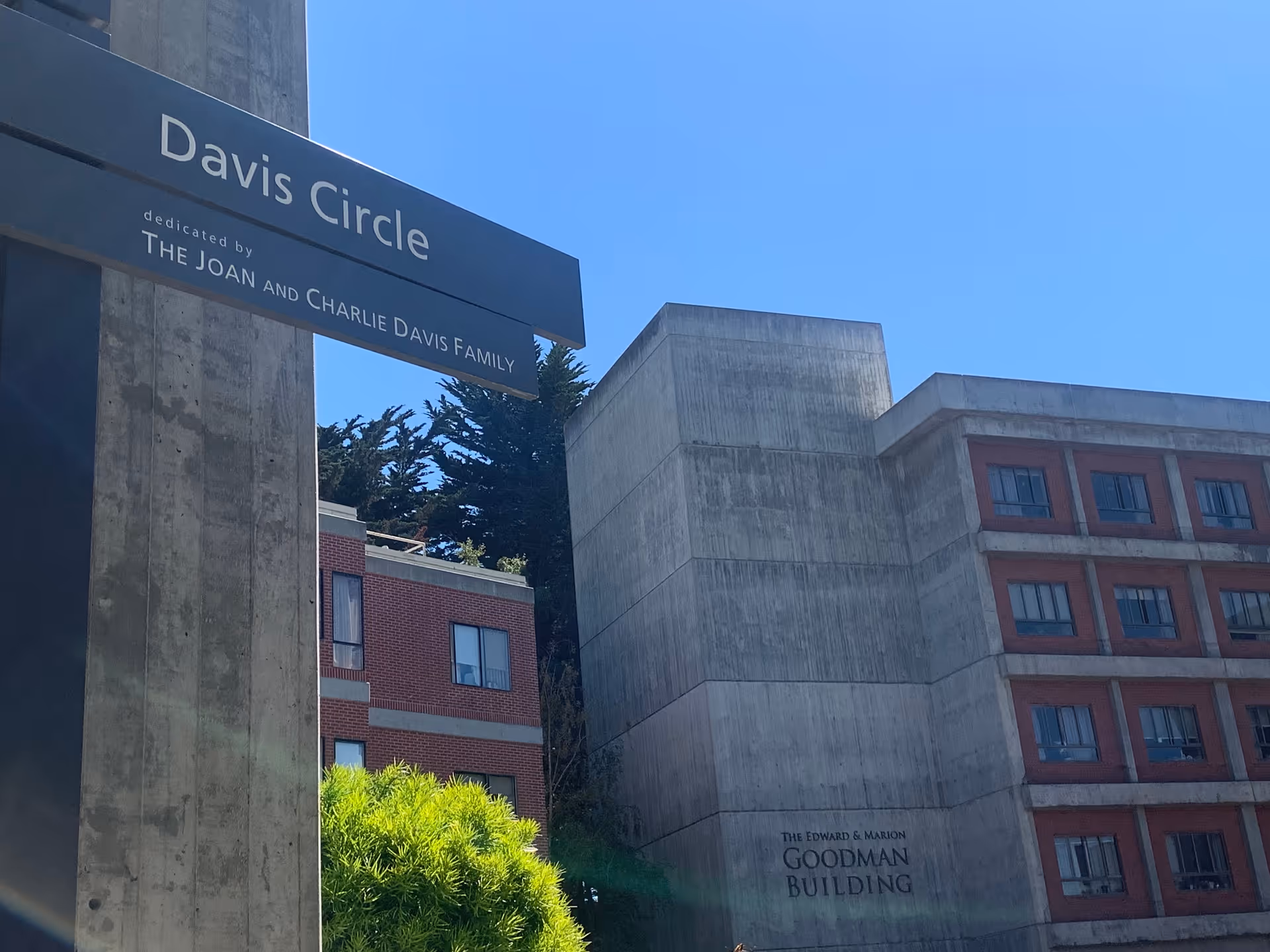 Davis Circle sign with campus concrete buildings and Goodman Building visible