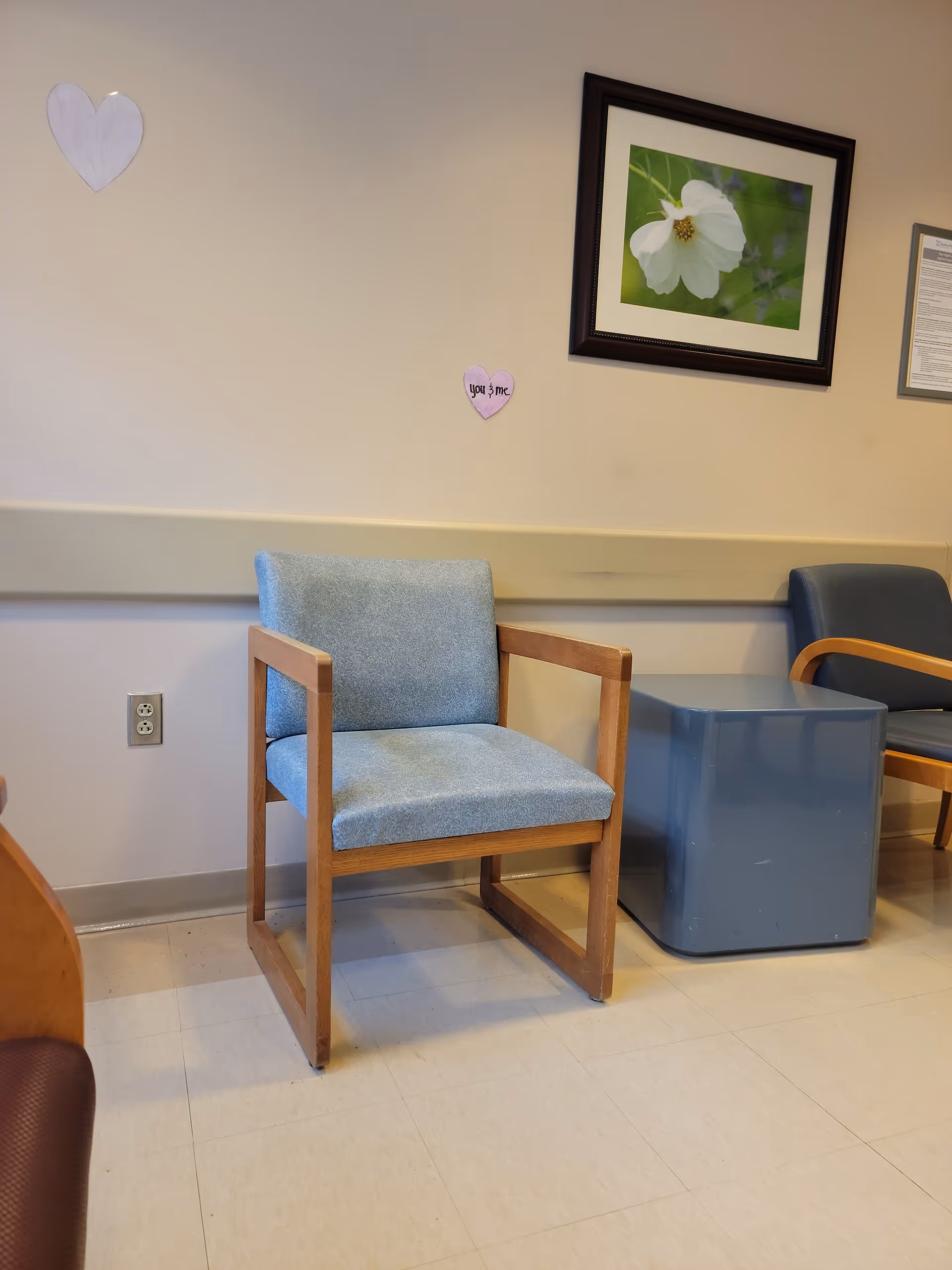Blue upholstered chair with wooden frame in a hospital waiting area.