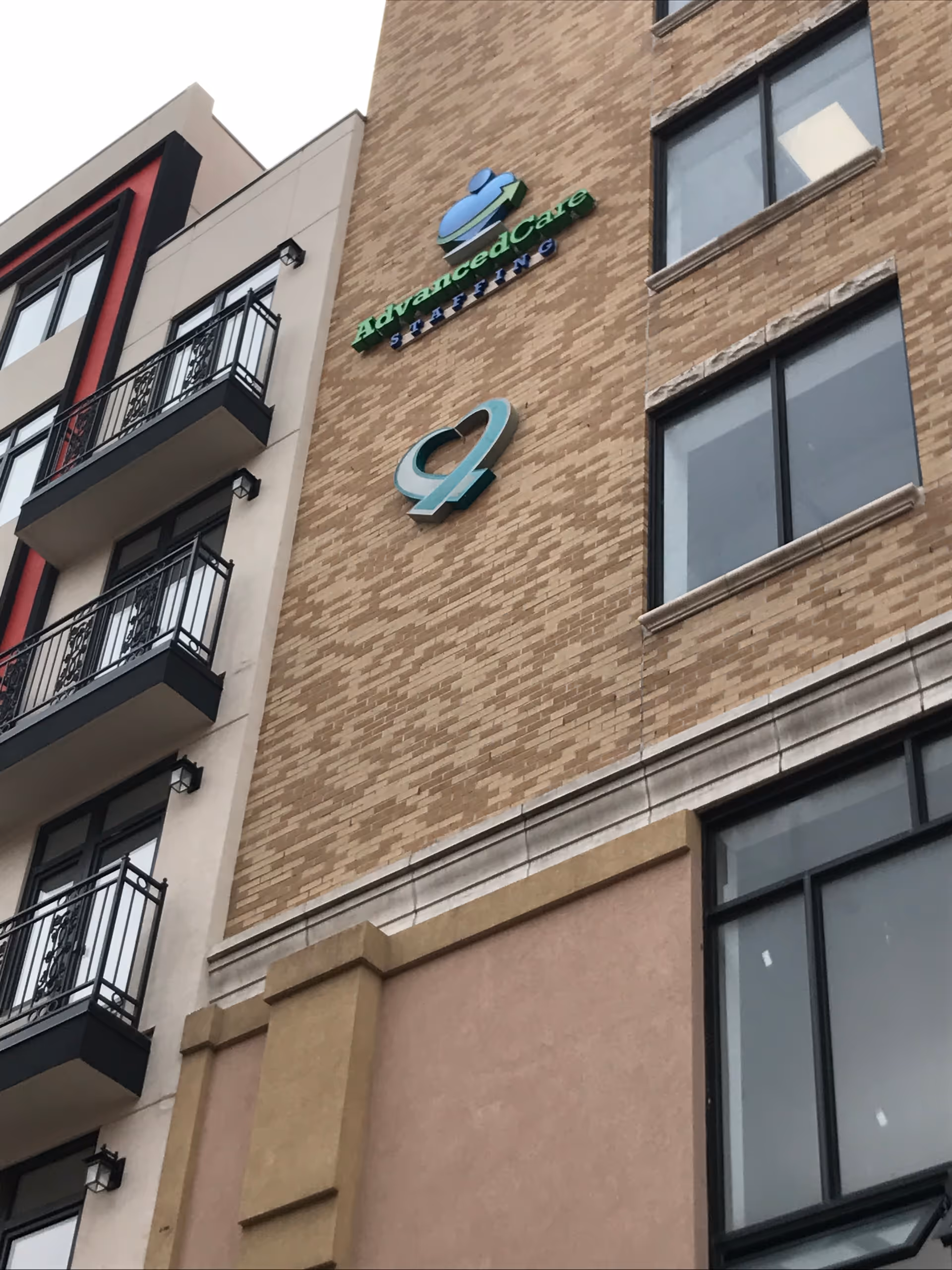 Brick exterior of a multi-story senior care building with signage and balconies.