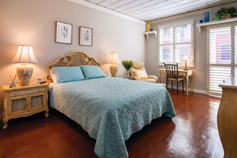 Spacious bedroom with a large bed, nightstands, desk, and bright windows.
