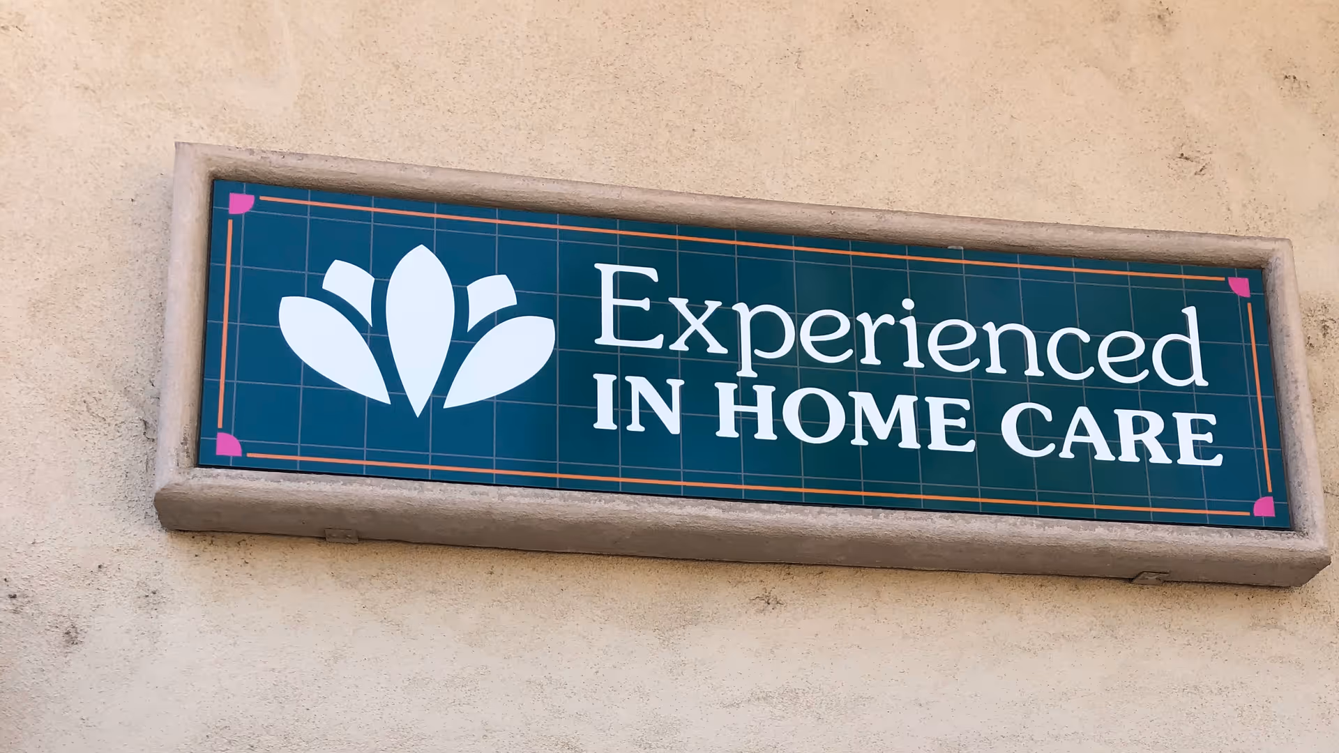 Signboard reading Experienced In Home Care mounted on a beige exterior wall.