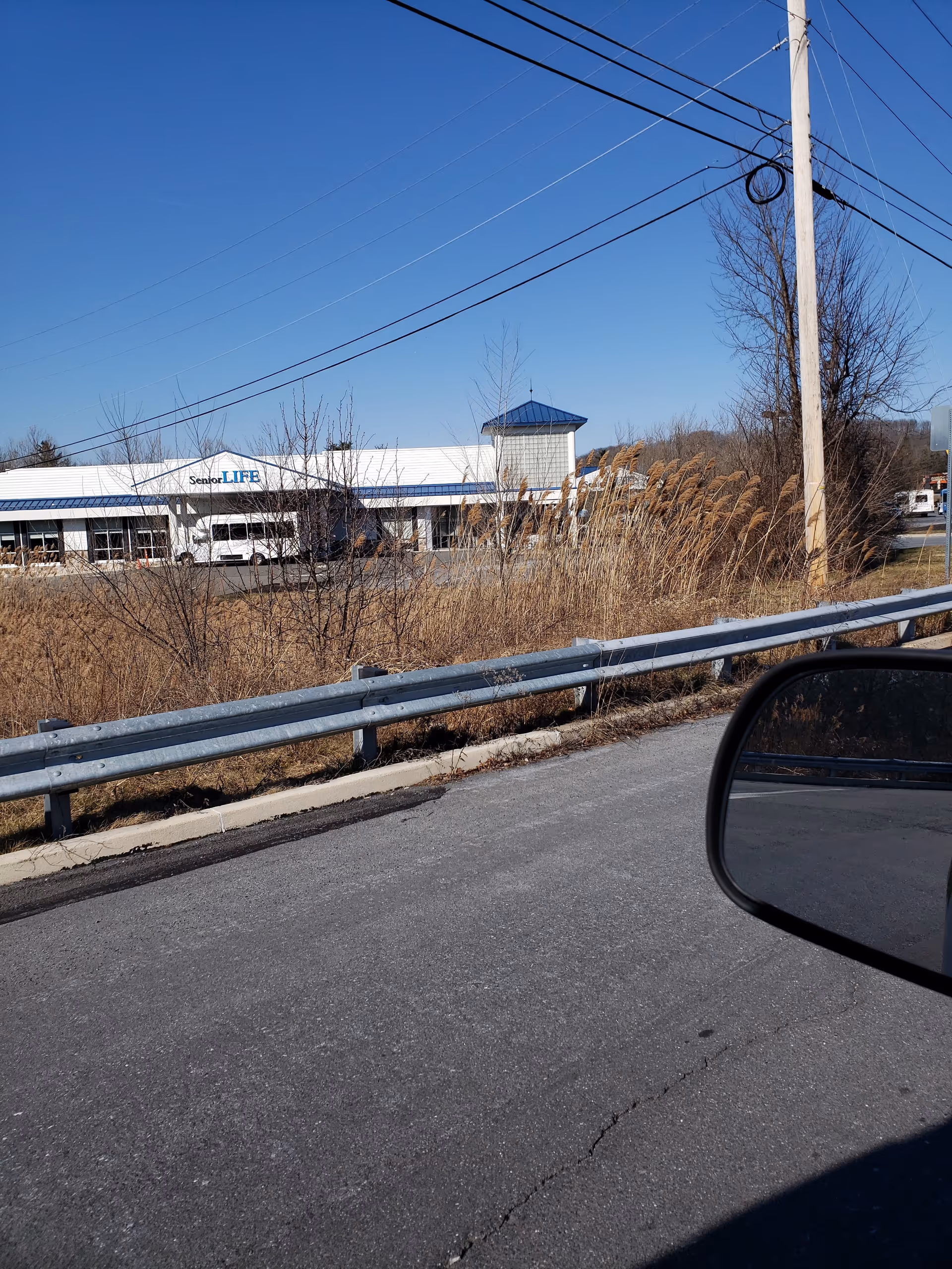 Exterior view of Senior LIFE building by road with blue sky and power lines.