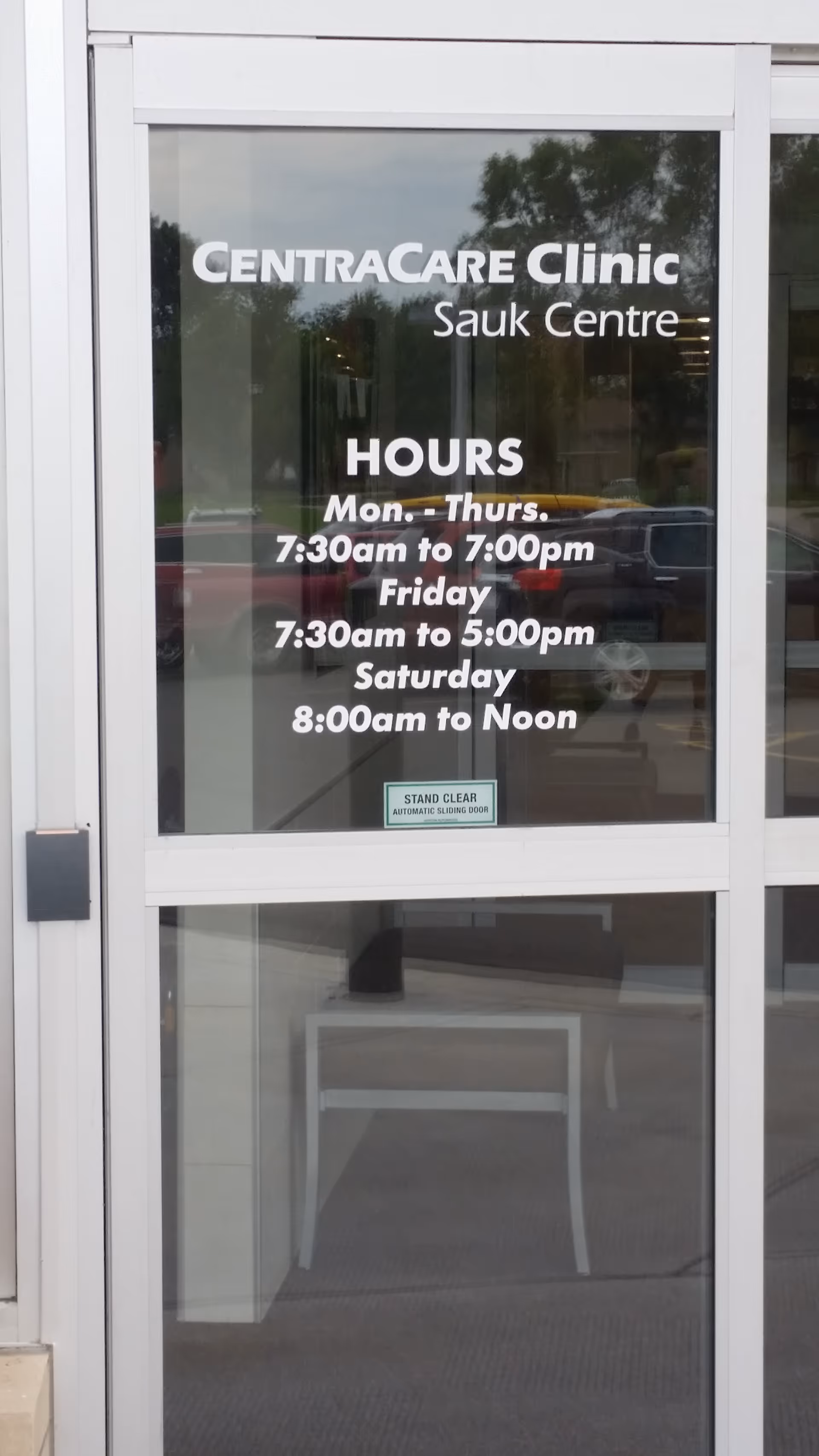 Glass entrance door displaying CentraCare Clinic Sauk Centre and hours.