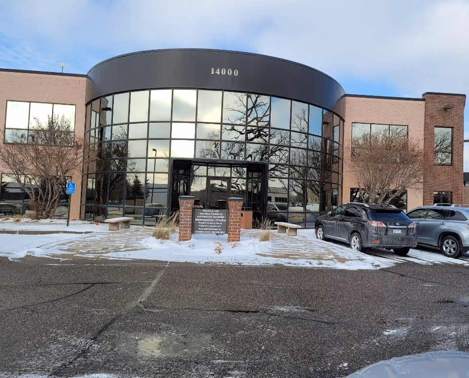 Exterior view of Lotus Care LLC building with curved glass entry and snow.