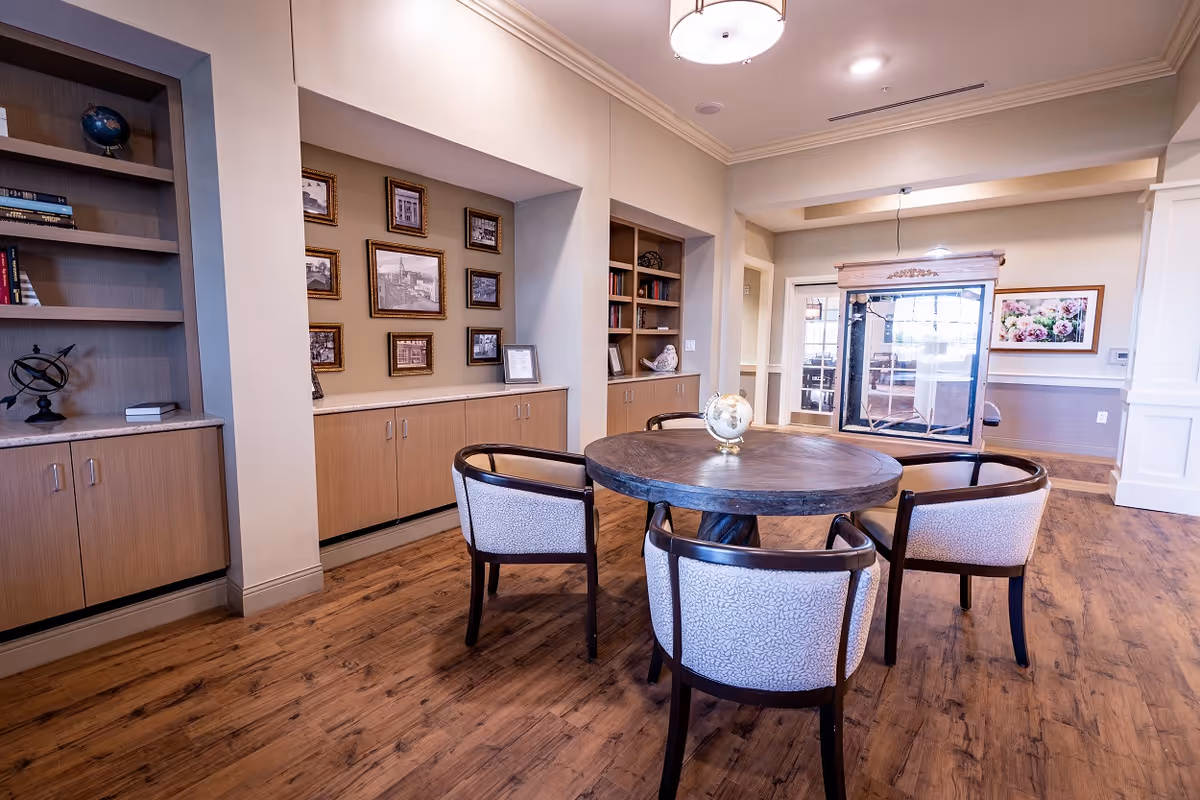 A cozy interior dining area with a round table, chairs, built-in cabinets, and framed photos.