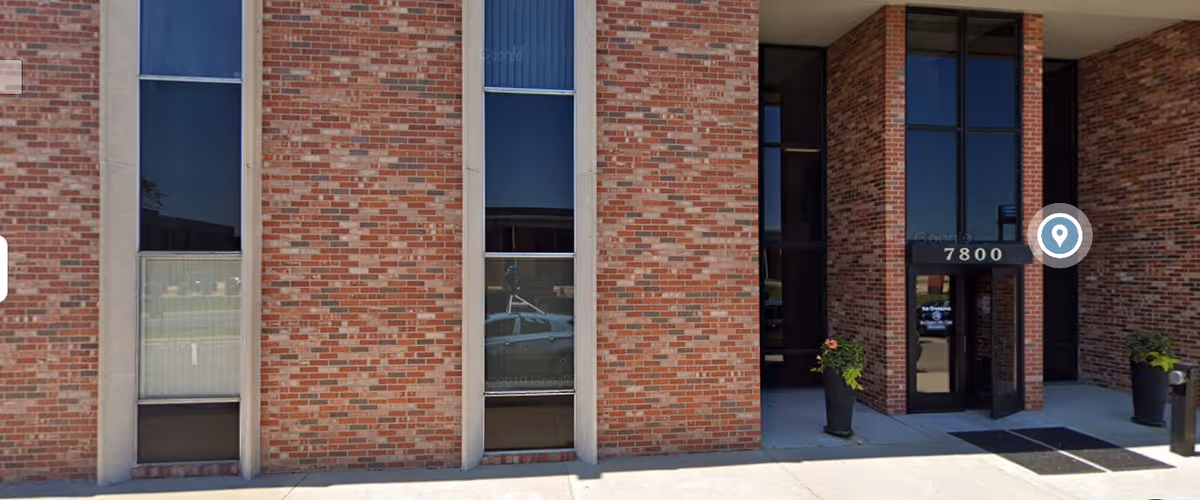 Exterior brick facility entrance with large windows and planters.