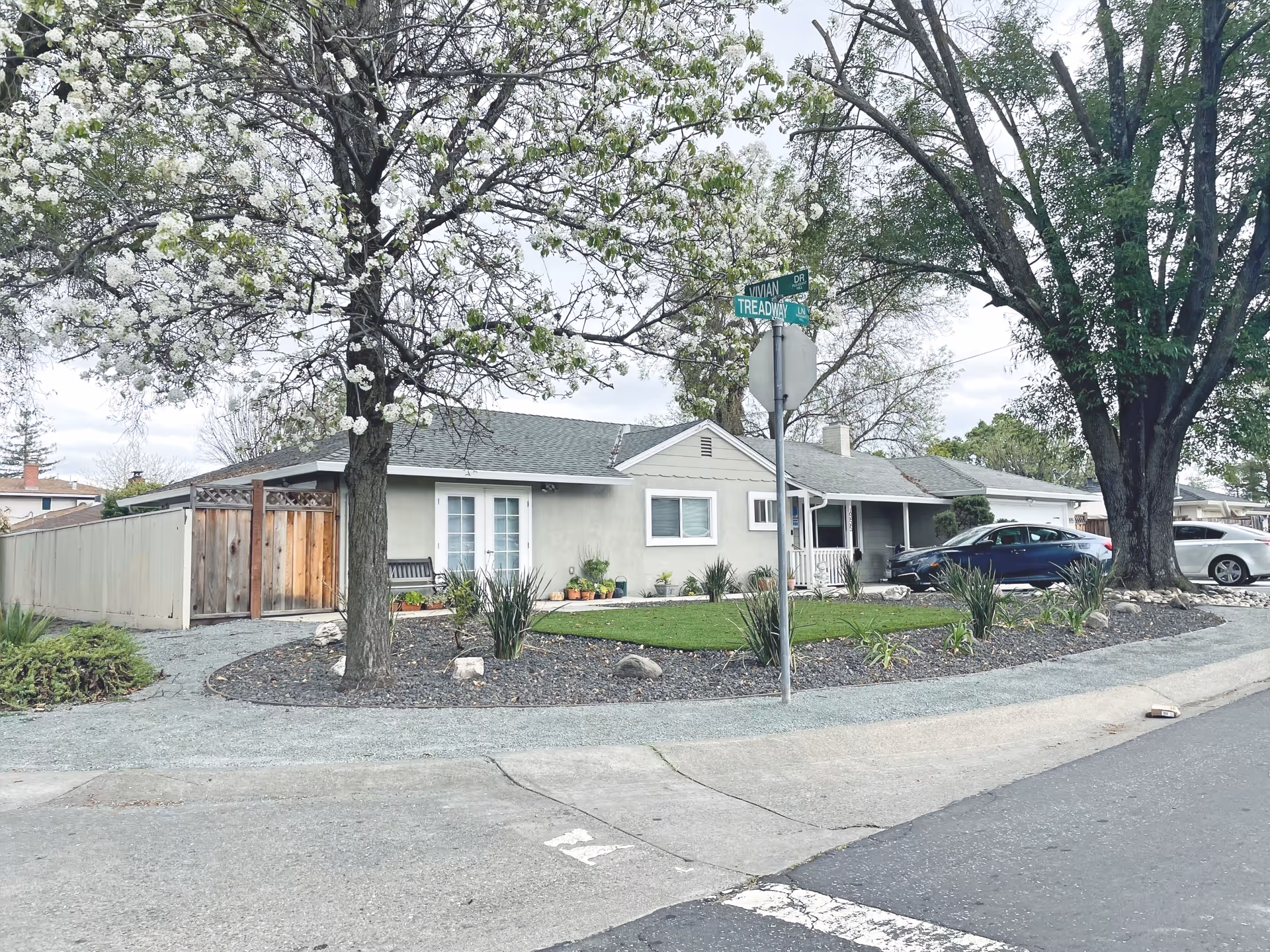 One-story facility with light siding, manicured yard, trees, and parked cars along the street.