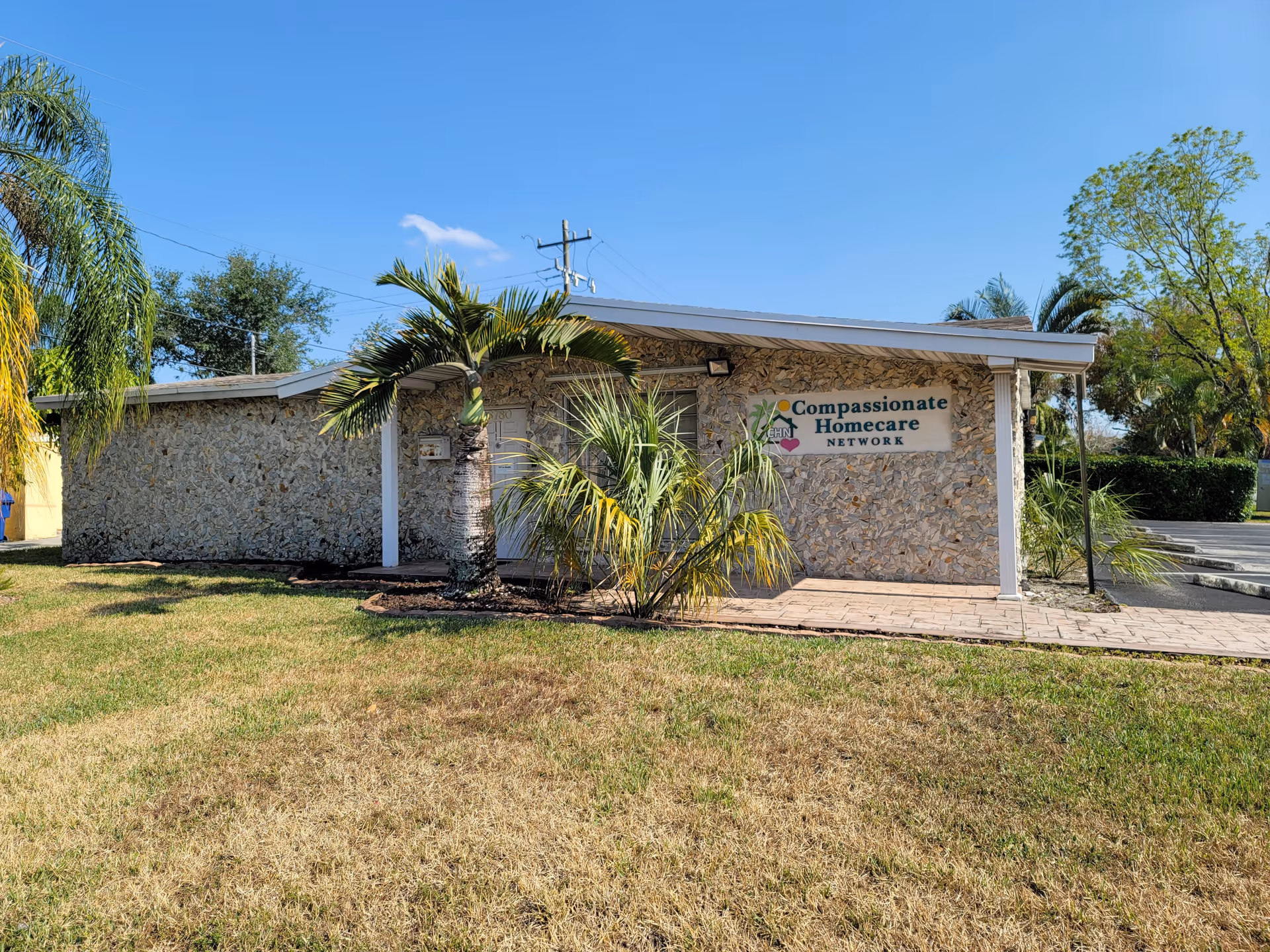 Front view of Compassionate Homecare Network building with palm trees and stone facade.