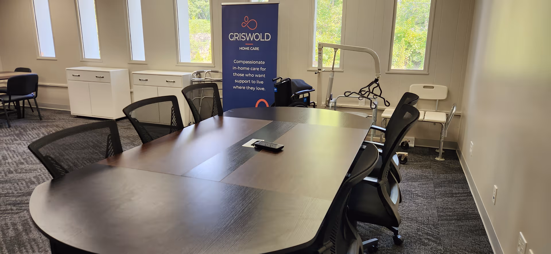 Bright conference room with a large table, chairs, and Griswold banner inside a care facility.