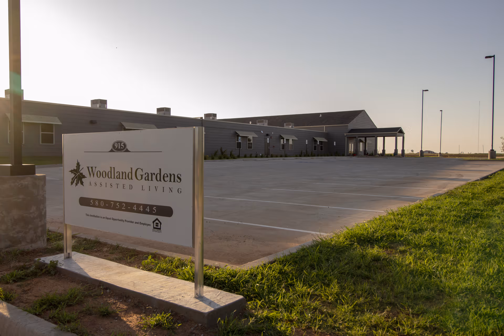 Woodland Gardens Assisted Living exterior with a large sign and empty parking area.