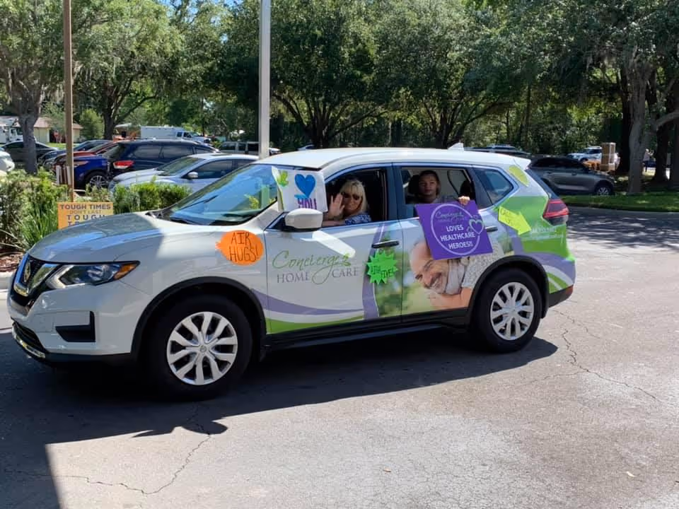 A decorated Concierge Home Care van is parked in a sunny lot with smiling passengers.