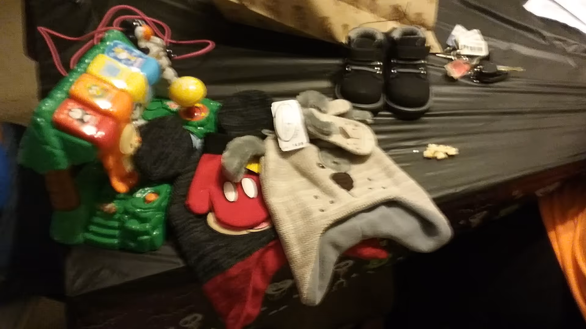 Cluttered bed surface showing shoes, socks, and a colorful toy.
