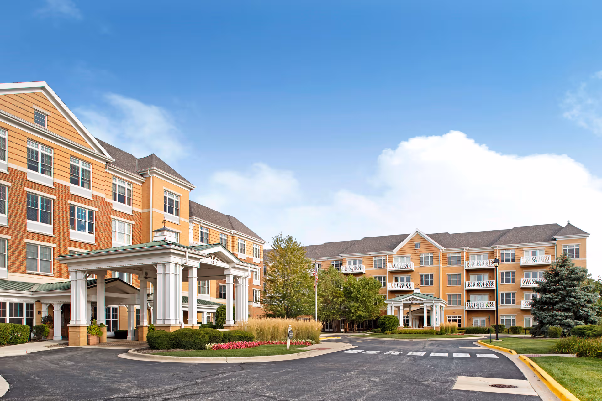 Sunny exterior view of Sunrise at Fountain Square with a porte-cochere and entry.