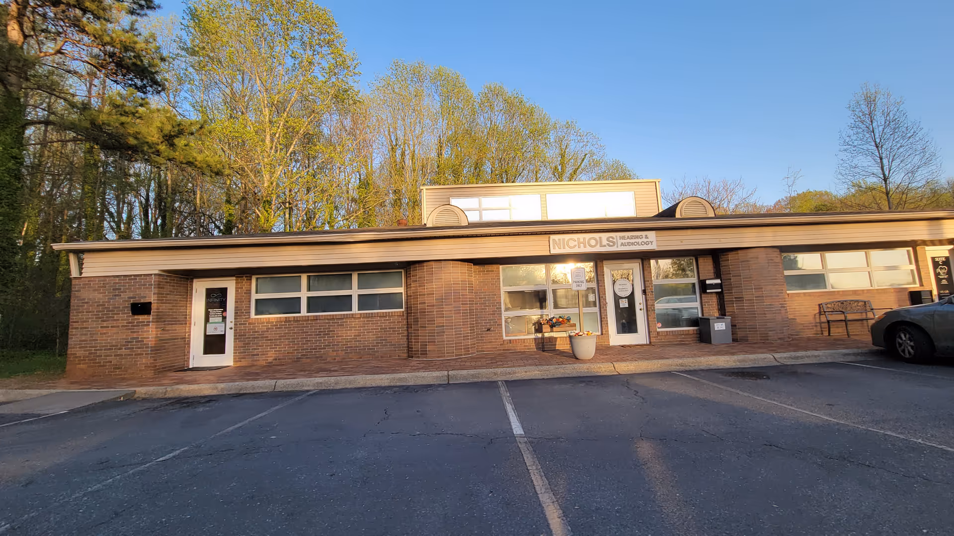 Brick, single-story building with a front entrance, Nichols sign, and a small parking lot.