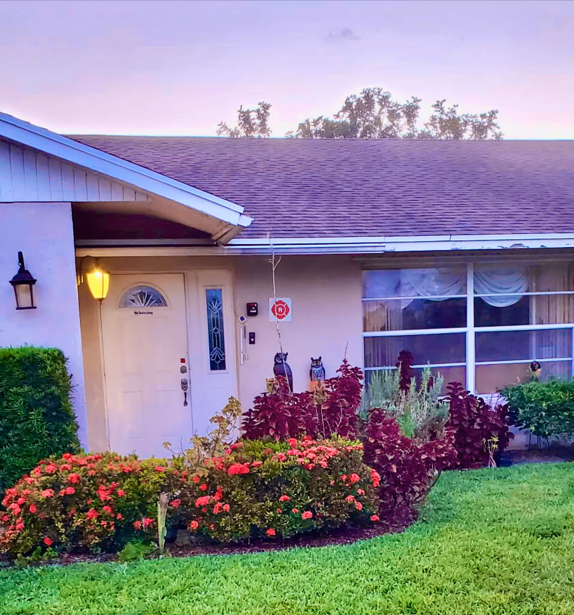 Front entrance of a single-story assisted living home with a landscaped garden.