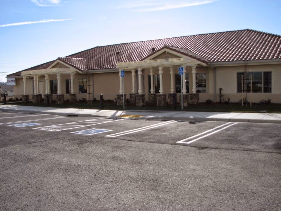 Single-story beige building with a red tile roof and accessible parking spaces in front.
