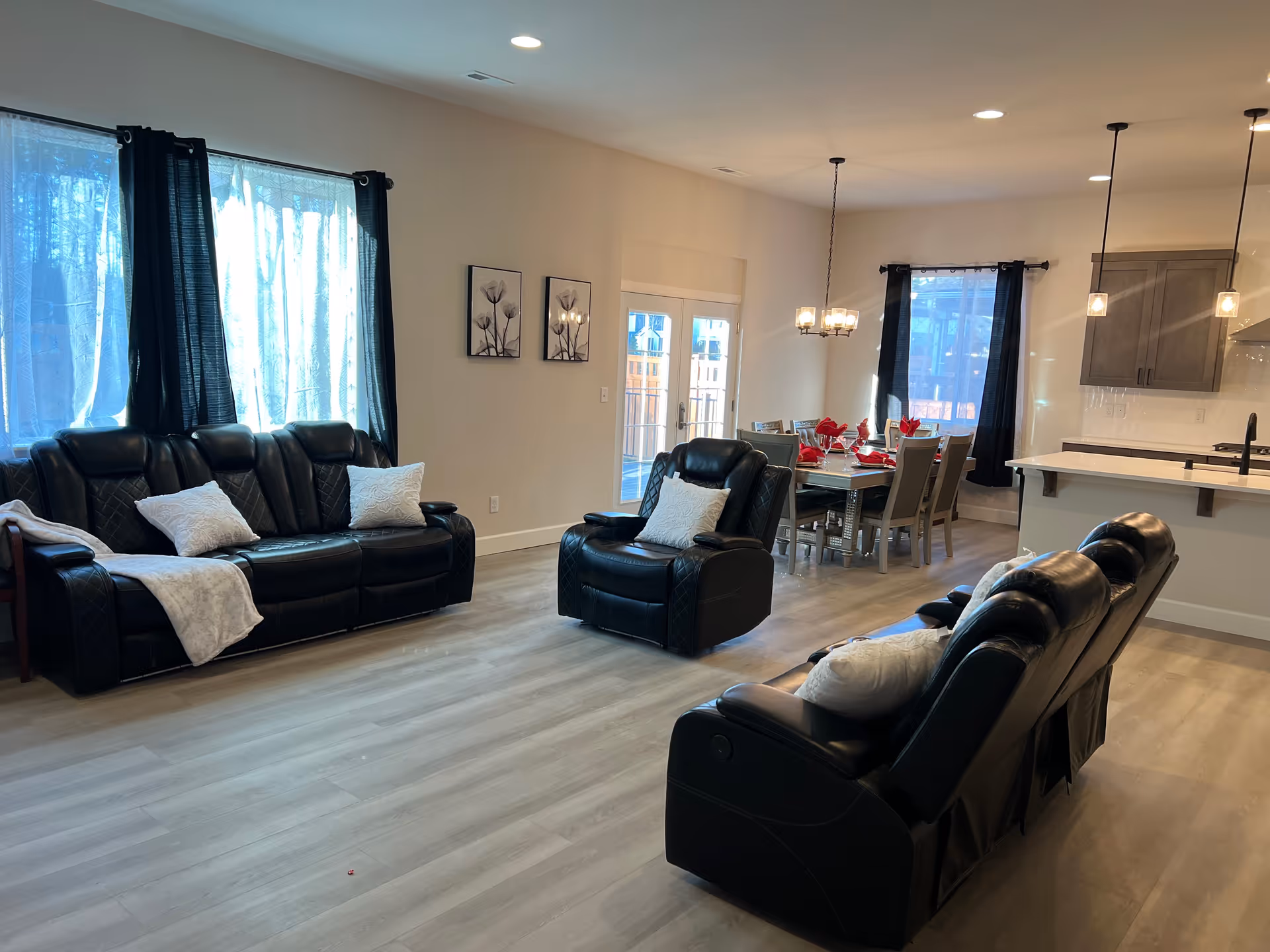 Spacious living area with black leather sofas, a dining table, and a kitchen island.
