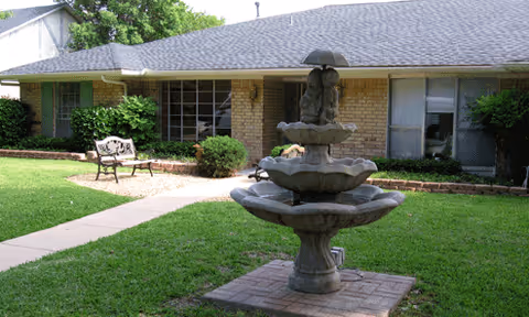 Front yard with fountain, bench, and brick building at Cameo Homes - Mariners.