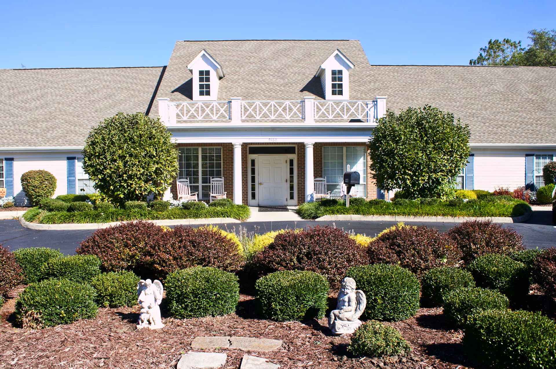 Front view of Abbington of Pickerington building with porch, manicured shrubs, and statues.