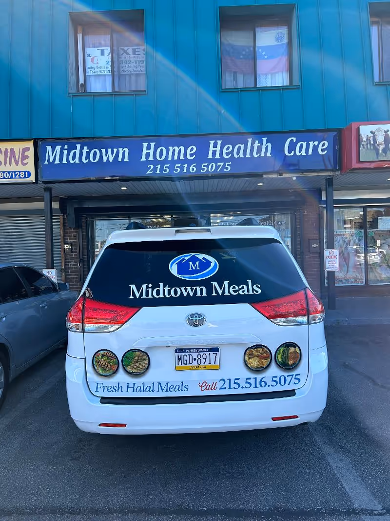 Blue storefront sign reads Midtown Home Health Care; white van labeled Midtown Meals parked.