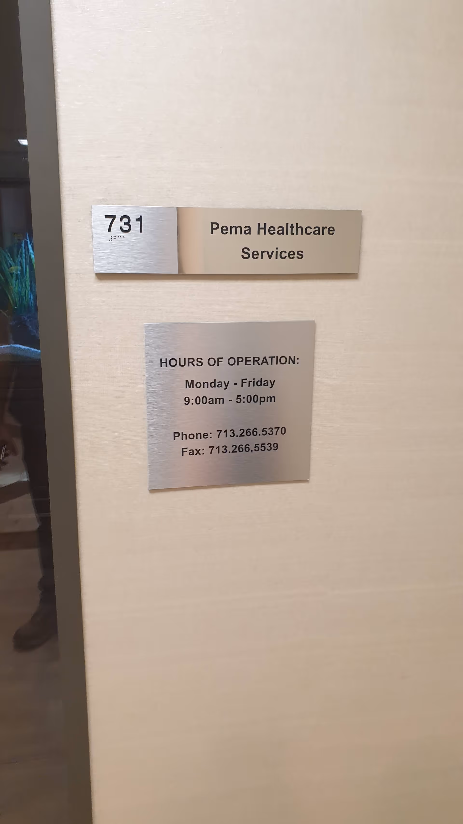 Interior hallway wall with metal plaques displaying Pema Healthcare Services and hours.