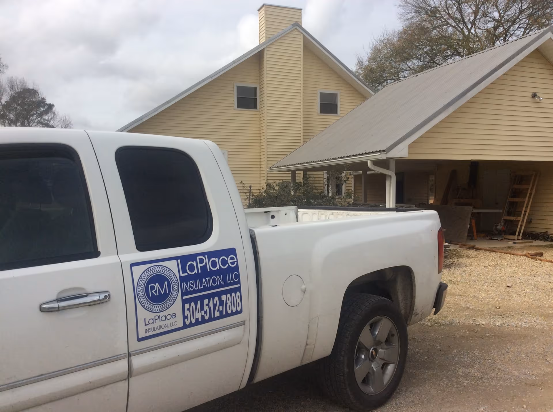 Exterior view of a beige house with a white pickup truck labeled RM LaPlace Insulation.