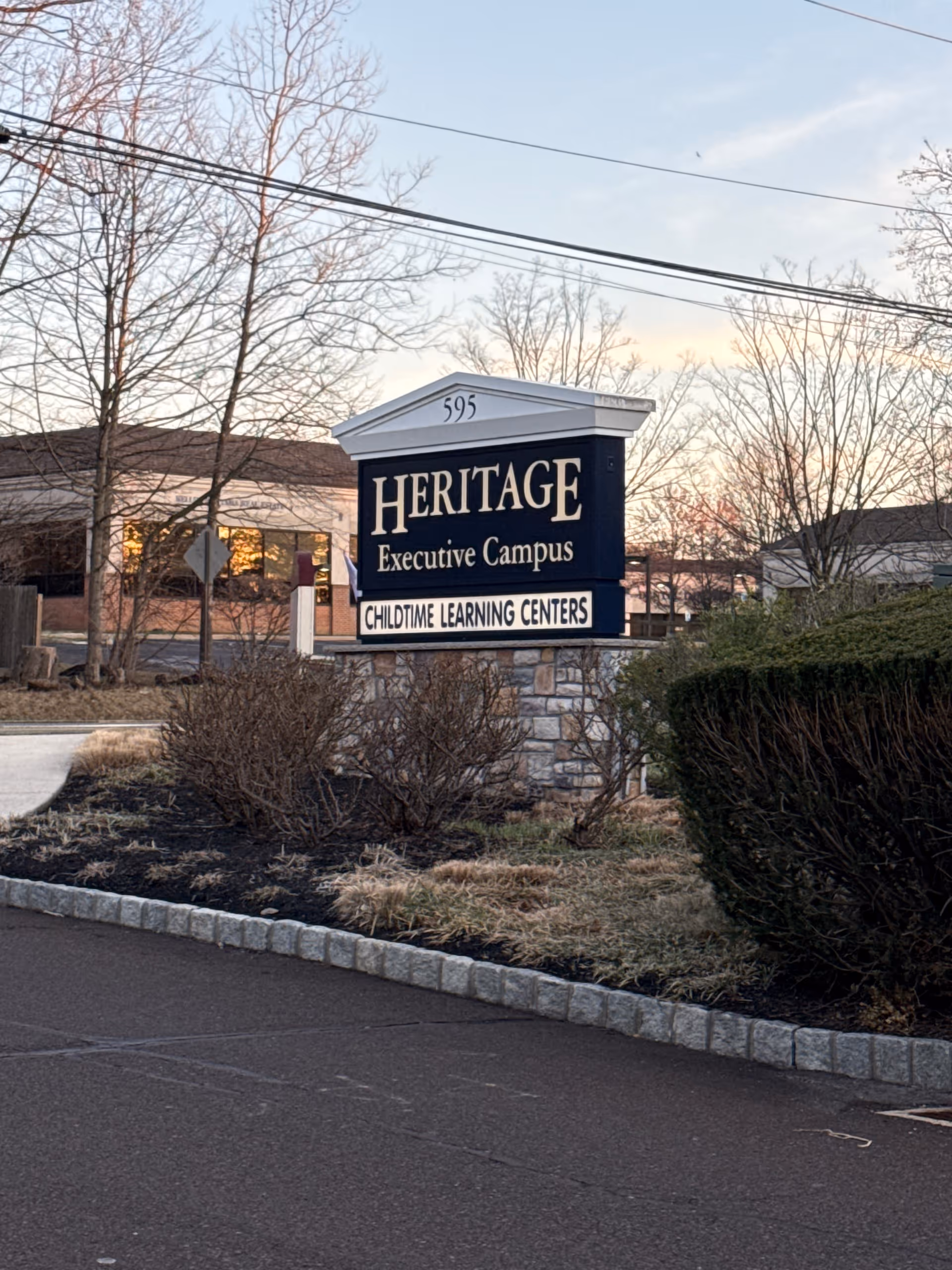 Exterior sign for Heritage Executive Campus and Childtime Learning Centers beside a parking lot.