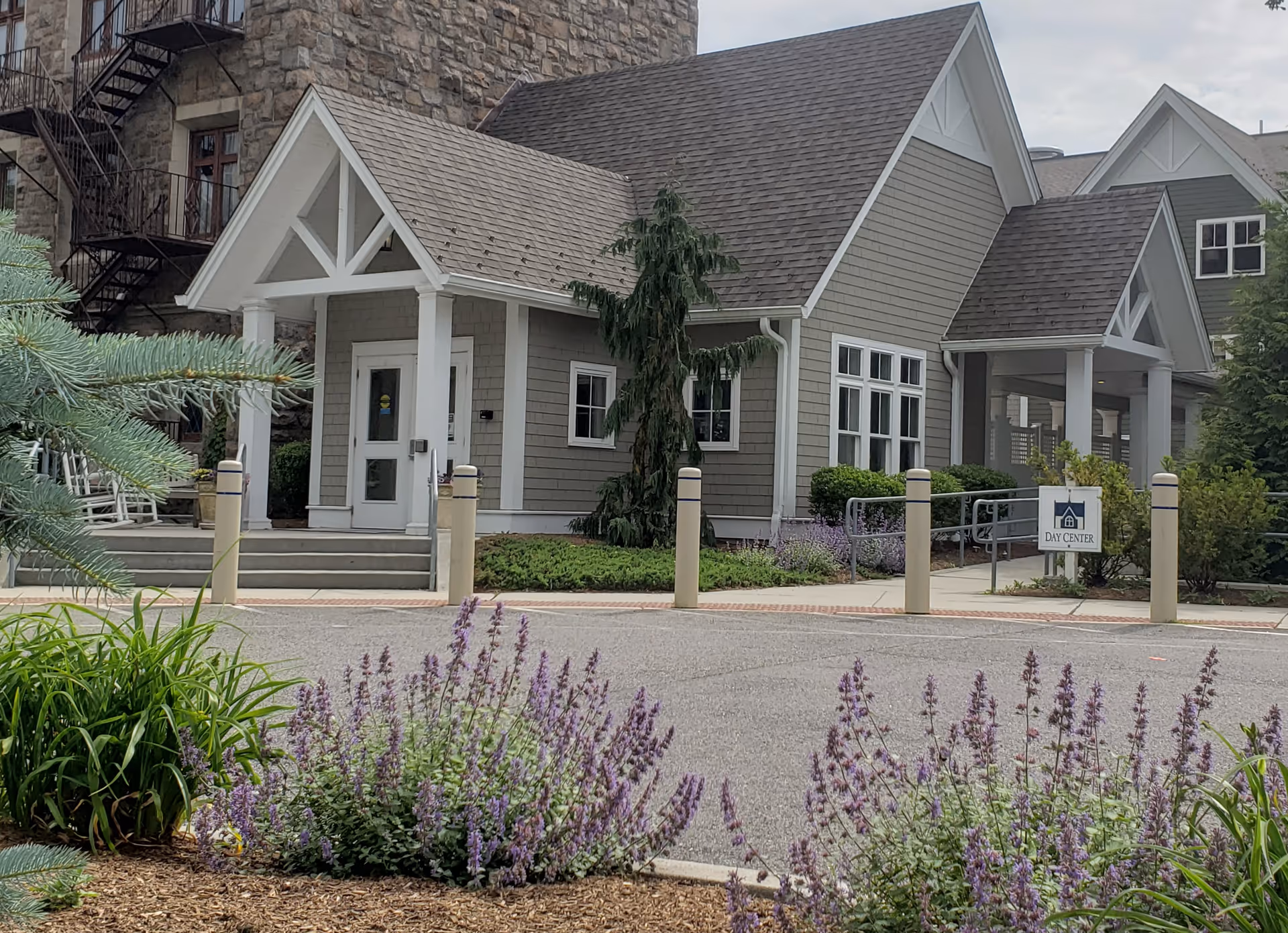 Exterior view of a gray senior center building with front entrance and landscaped surroundings.