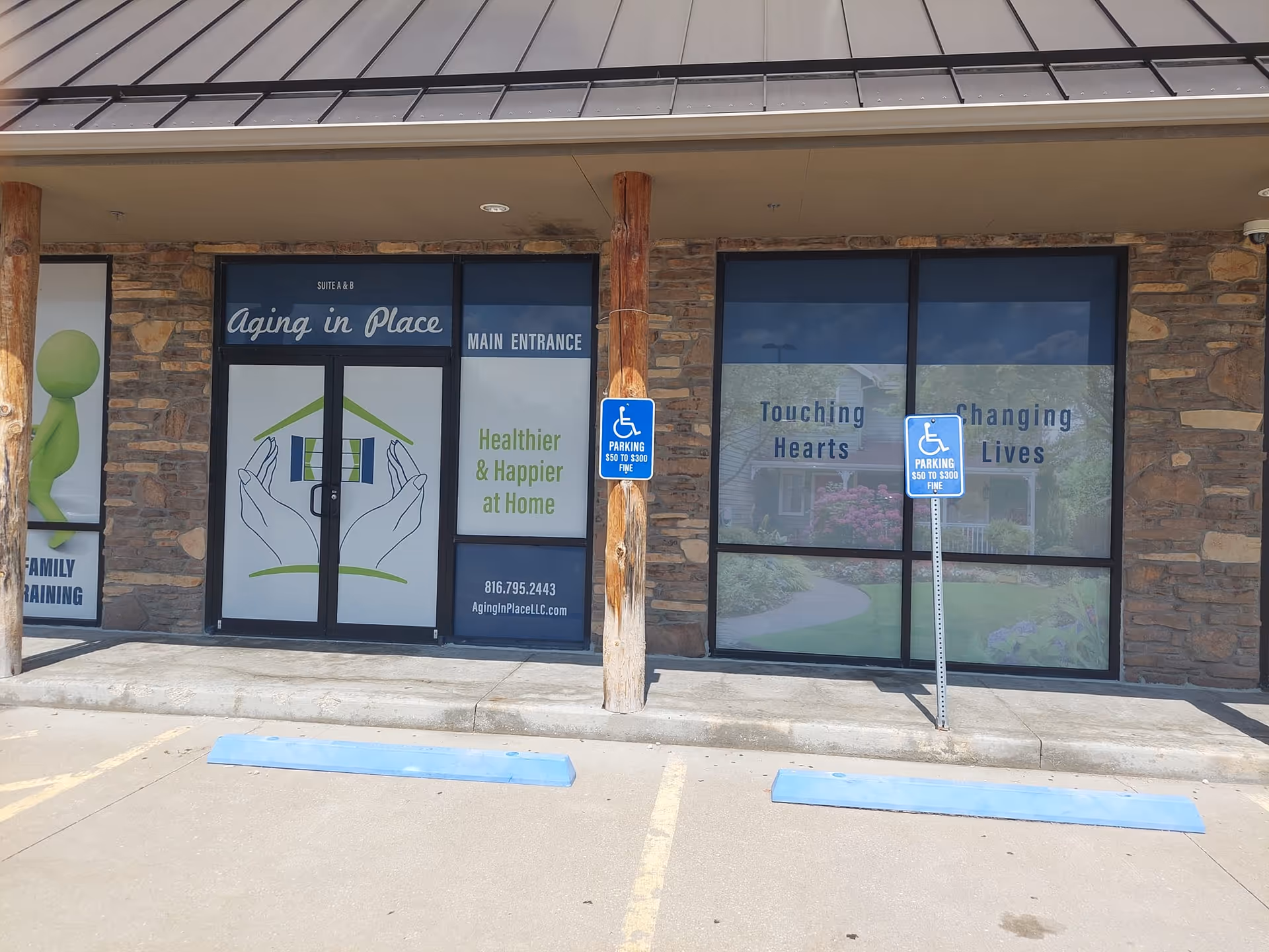 Exterior storefront of Aging In Place LLC with glass doors, signage, stone facade, and parking signs.