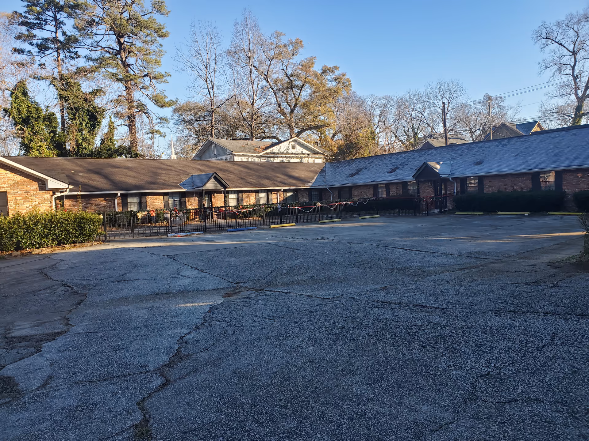 Single-story brick senior living facility with a long front facade and cracked parking lot.