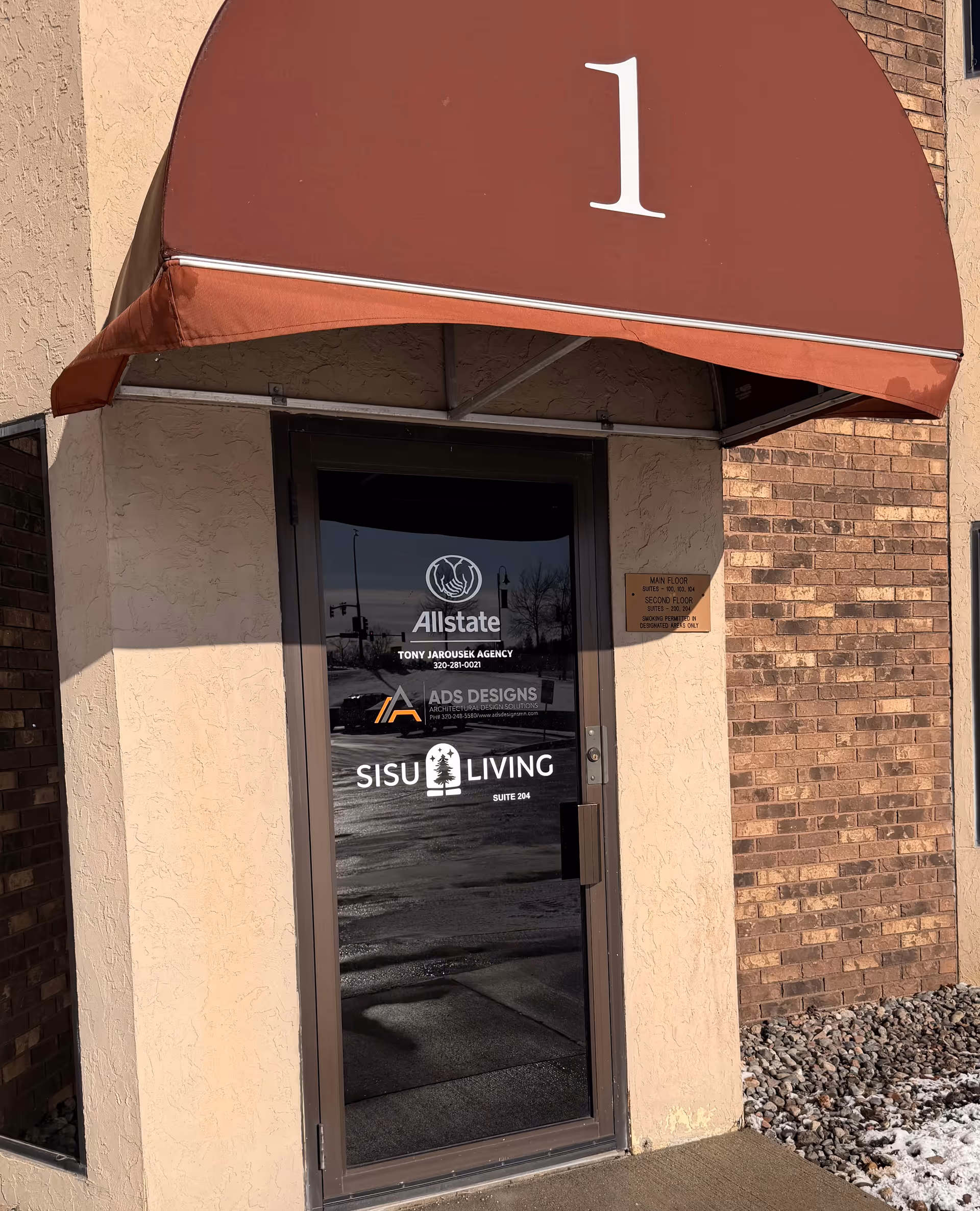 Entrance to Sisu Living LLC with a maroon awning displaying number 1.