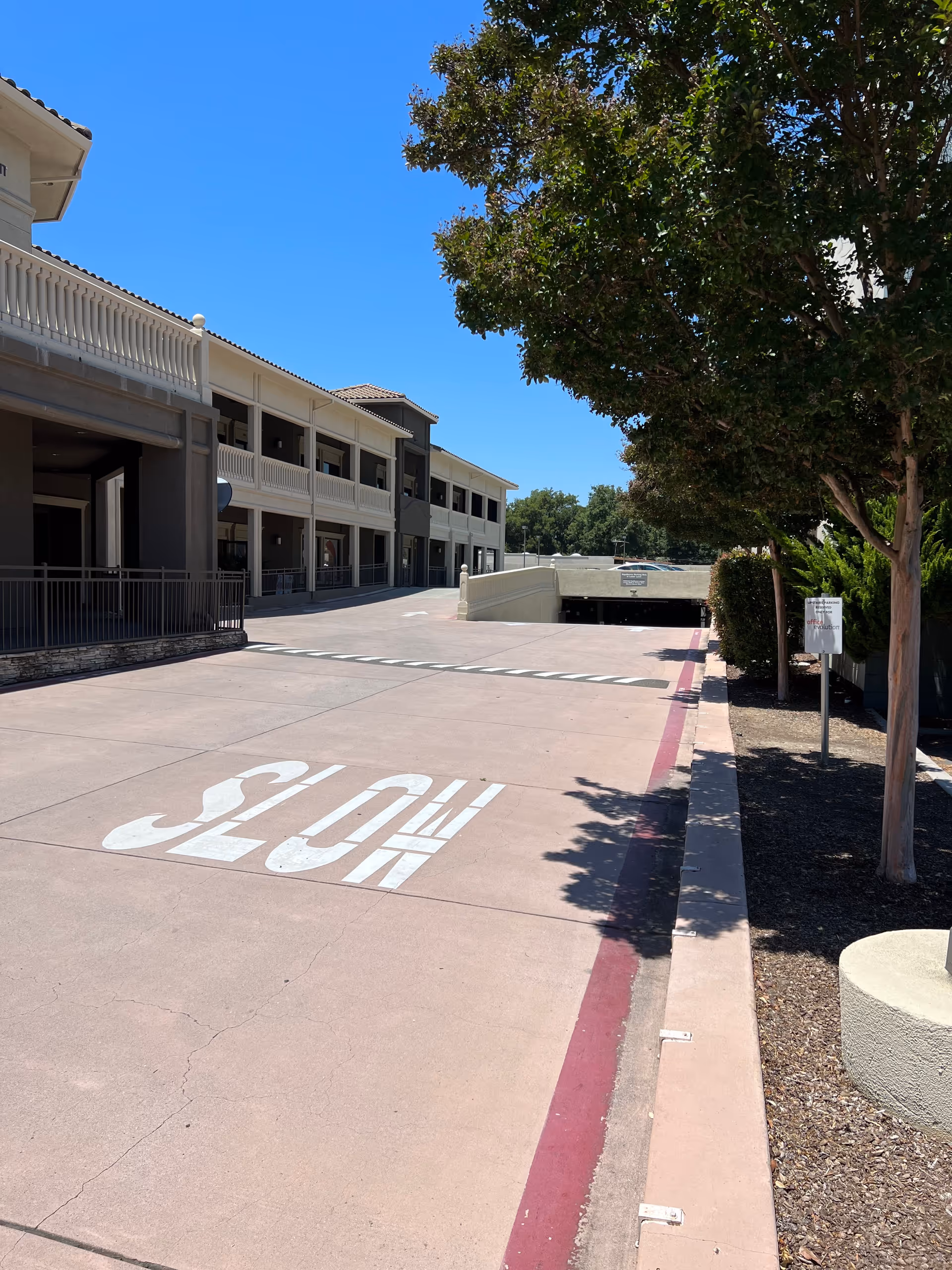 Two-story senior living facility exterior with a driveway, trees, and a large STOP marking