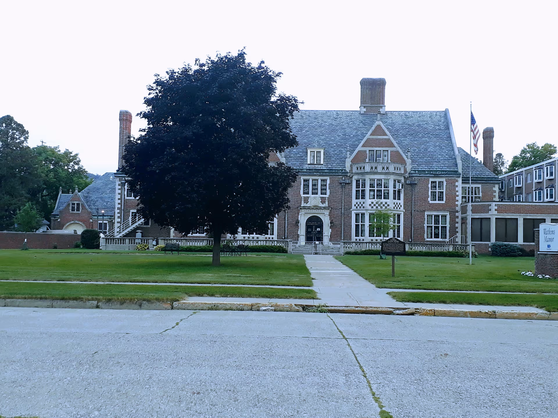 Front view of a large brick senior living facility with a manicured lawn