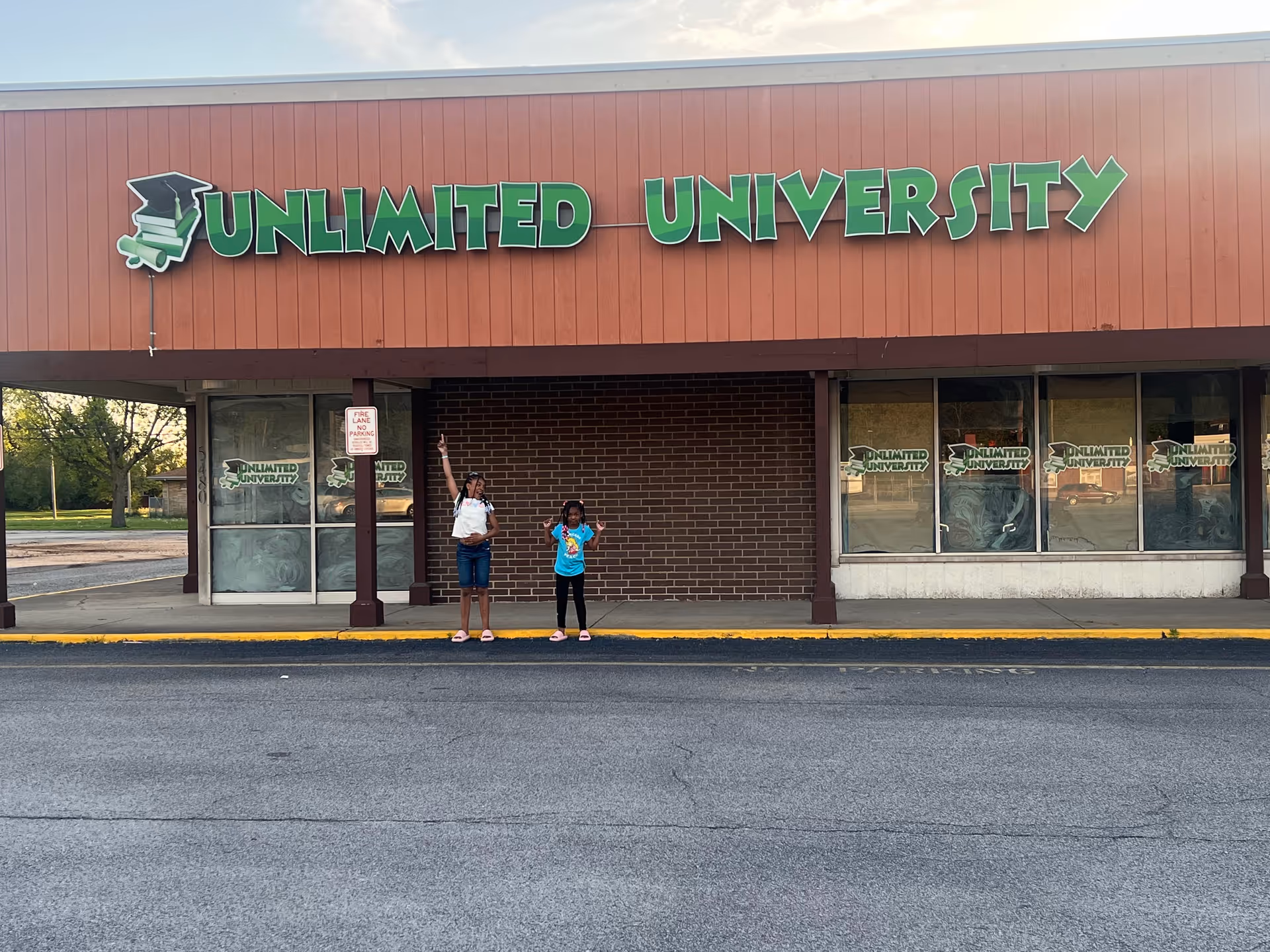 Exterior storefront with a large sign reading Unlimited University; two people on the sidewalk.