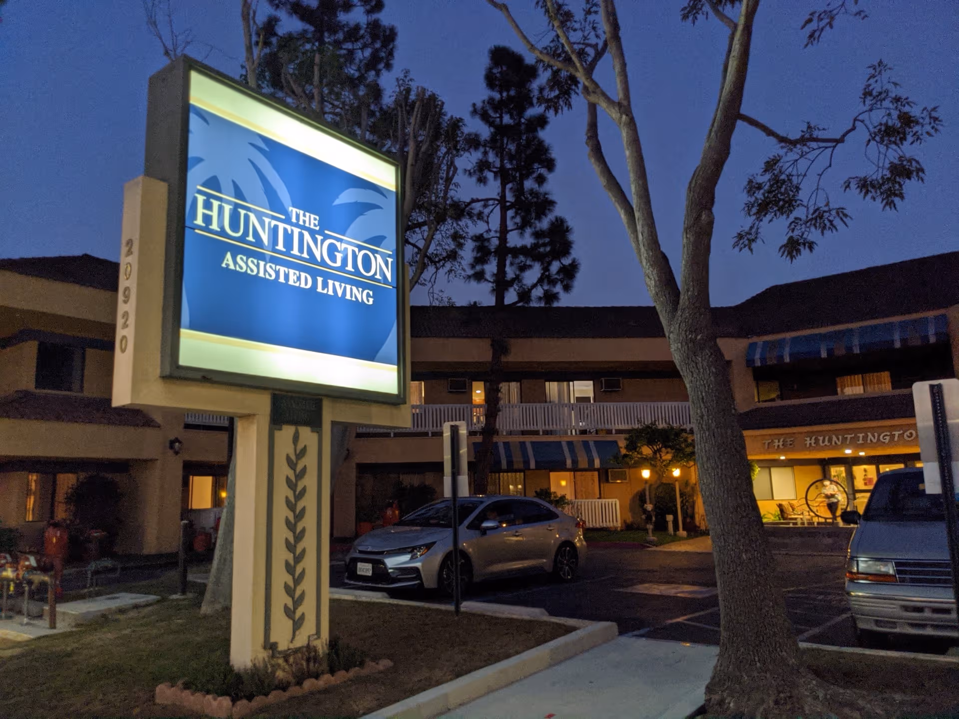 Evening exterior of Huntington Assisted Living with illuminated sign and front entrance