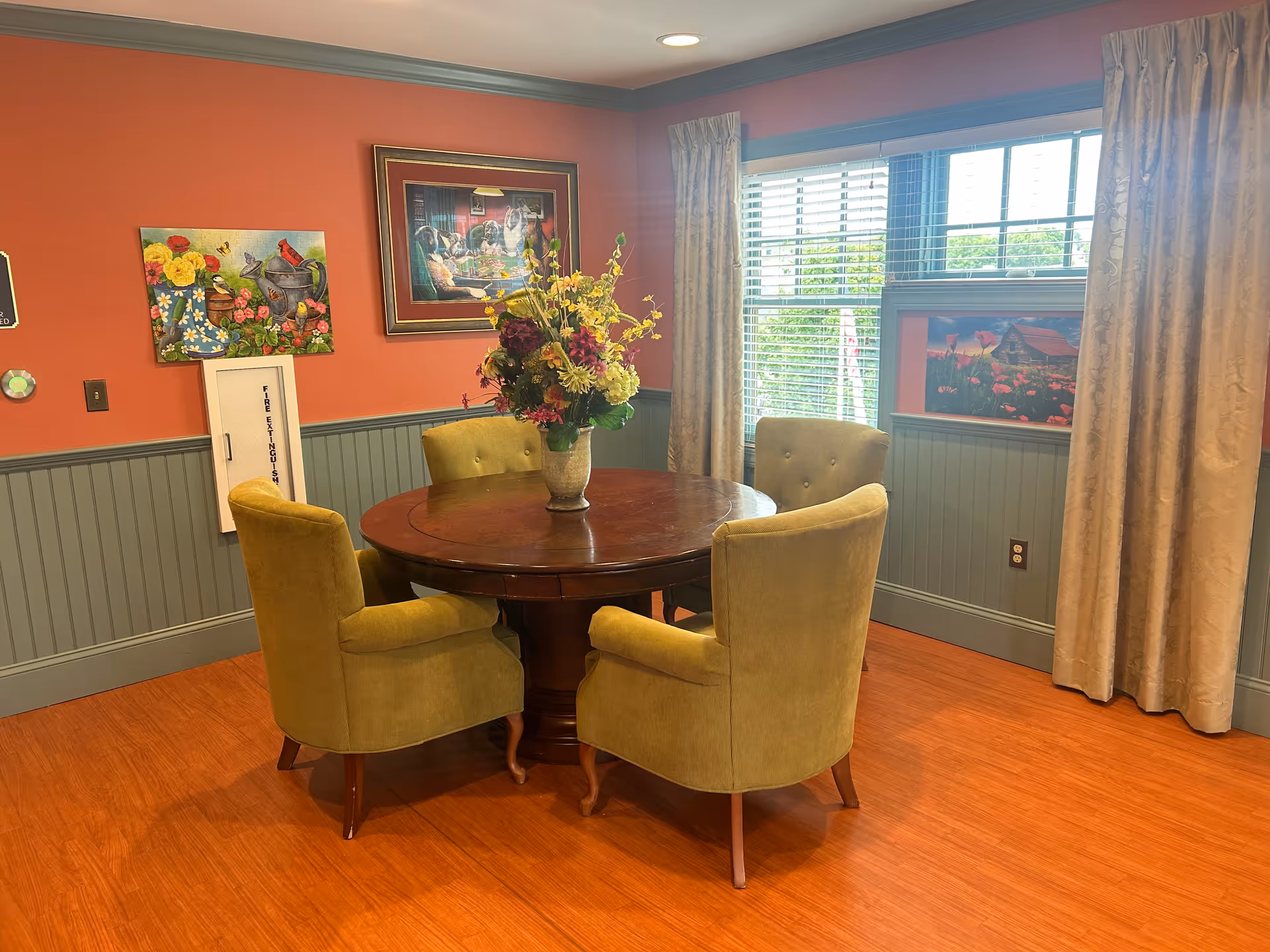 Round wooden table with four green upholstered chairs in a colorful dining room.