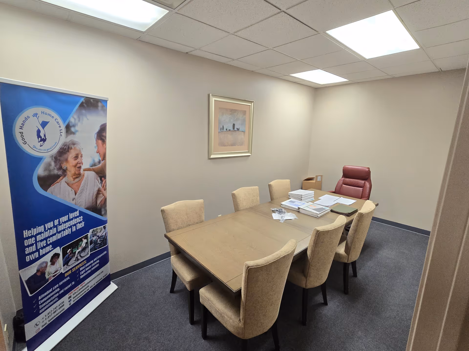 Meeting room in a senior care facility with a long table, beige chairs, and a banner.