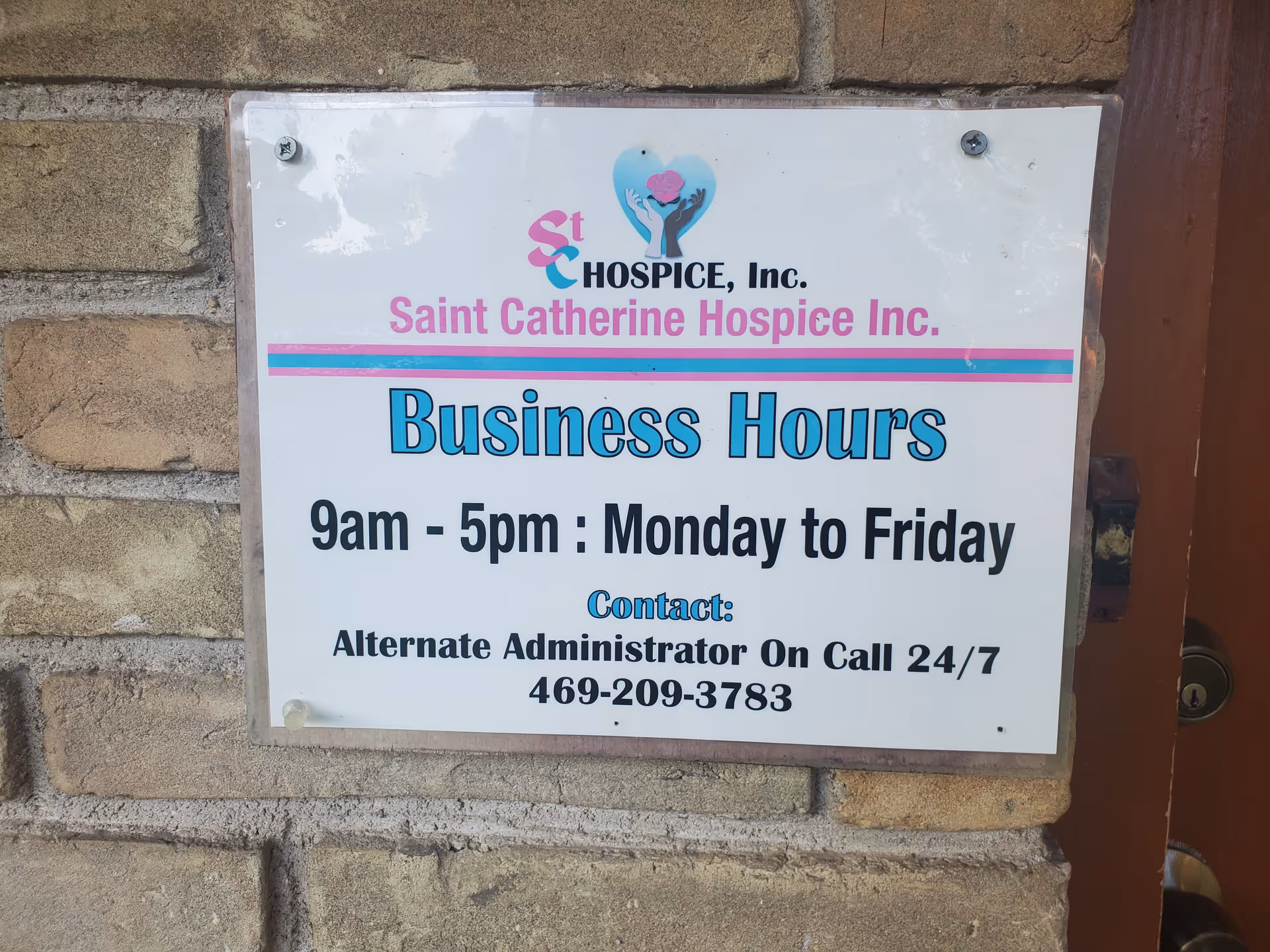 Sign on brick wall advertising Saint Catherine Hospice business hours