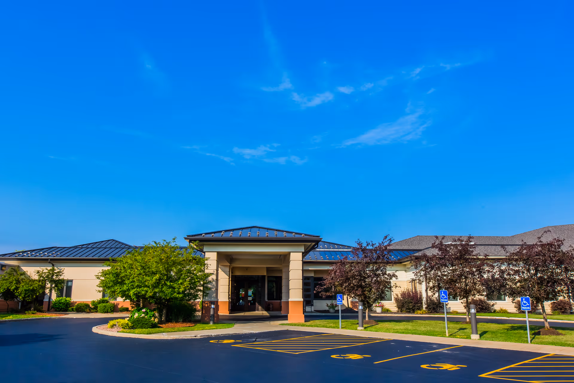 Sunny exterior view of Autumn View Health Care Facility entrance with parking.
