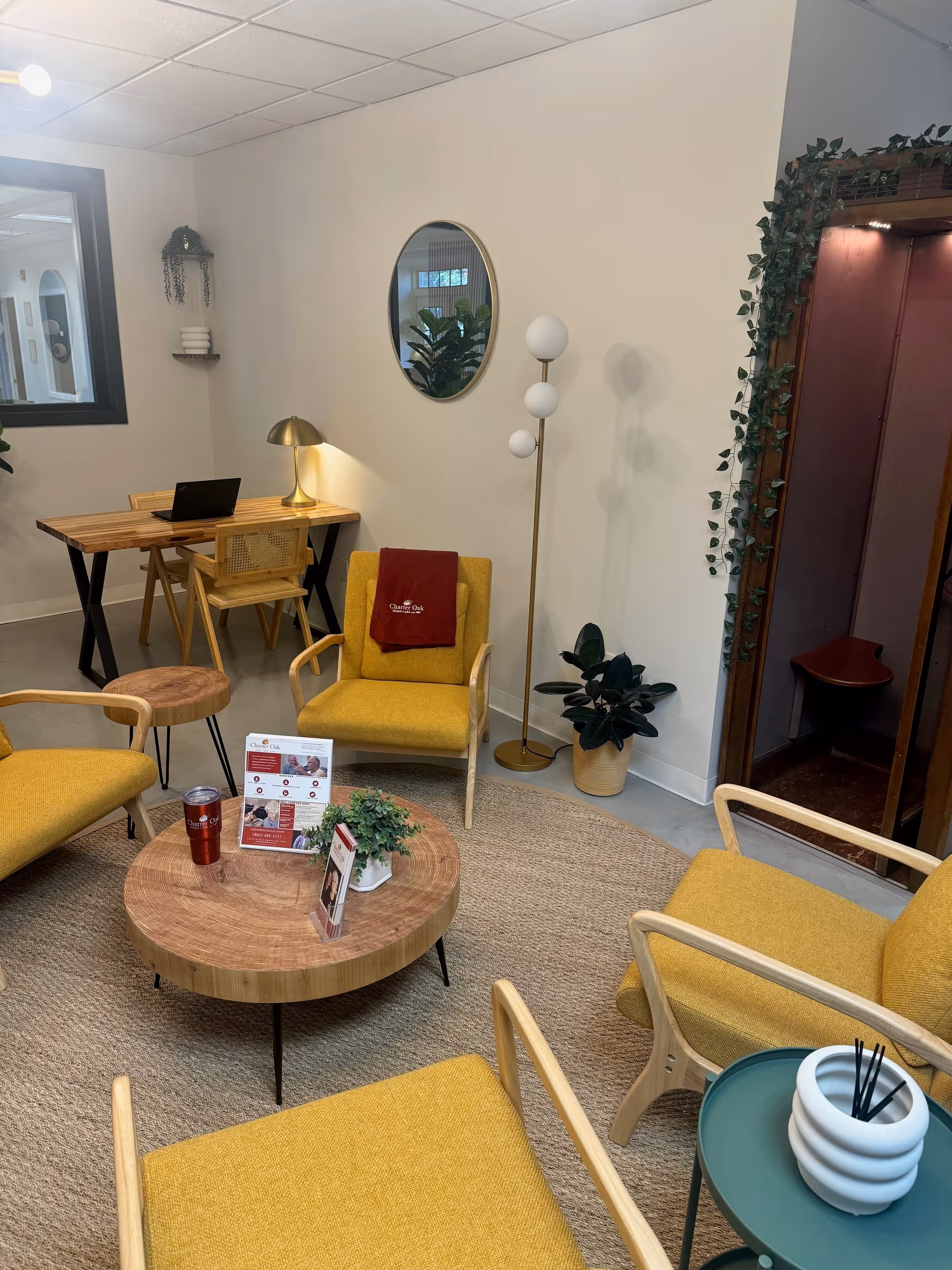 Cozy modern living lounge with mustard chairs, round coffee table, plants, and a desk.