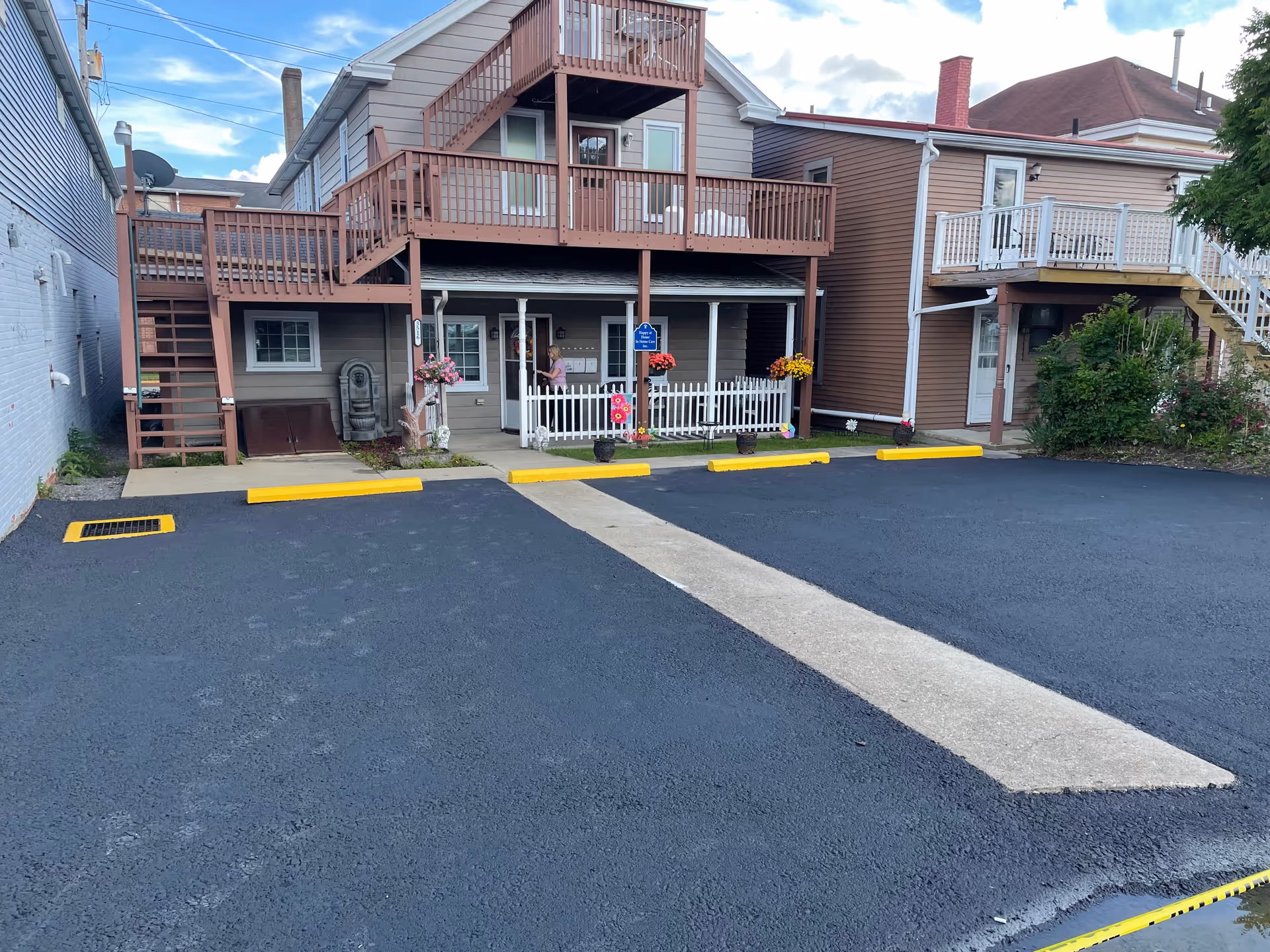 Exterior of a senior living building with balconies, a front porch, and a paved parking area.