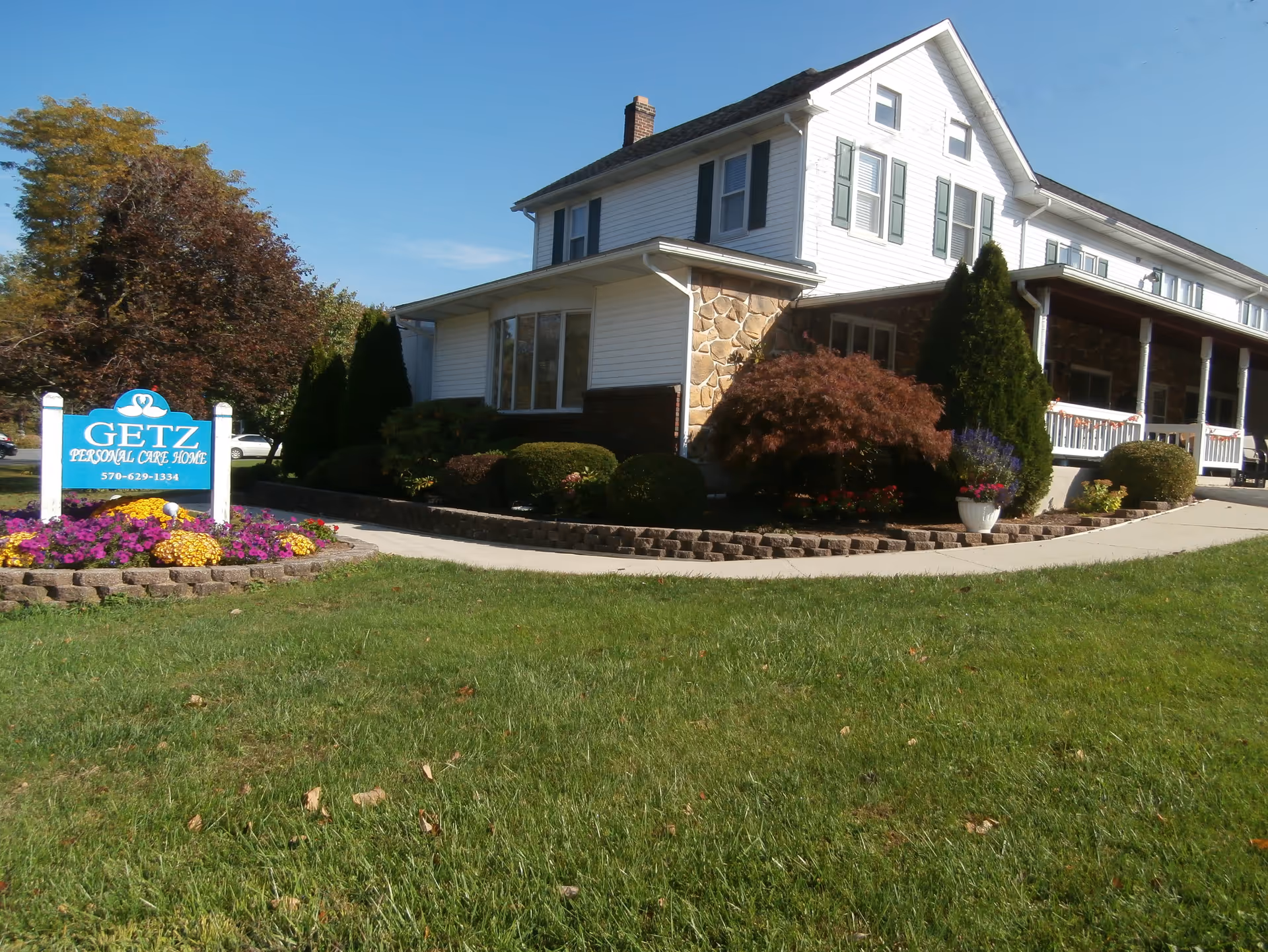 Two-story white building with stone accents, landscaped yard, and a Getz Personal Care Home sign.