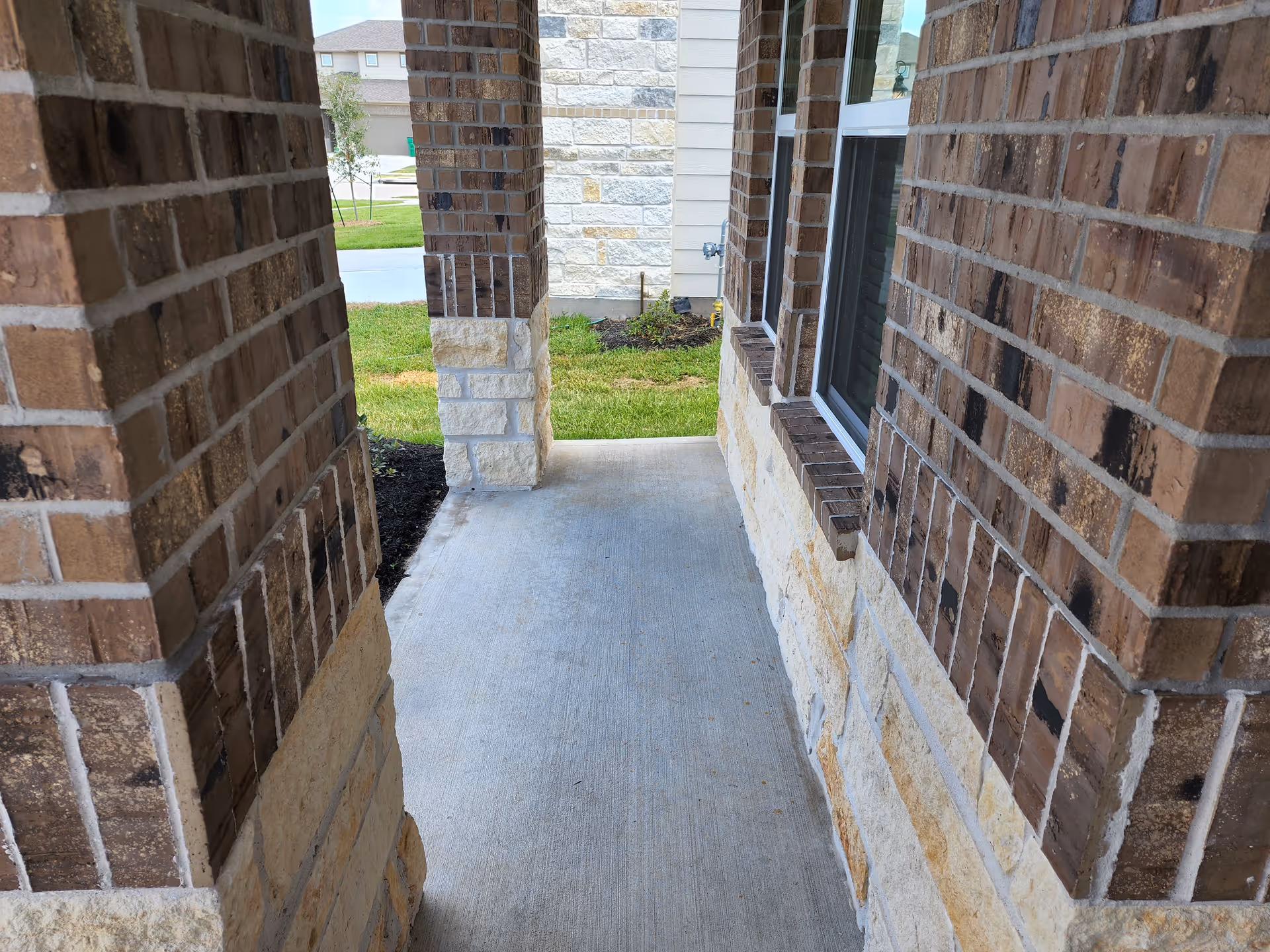 Exterior brick walkway between columns leads to a grassy yard at the care home