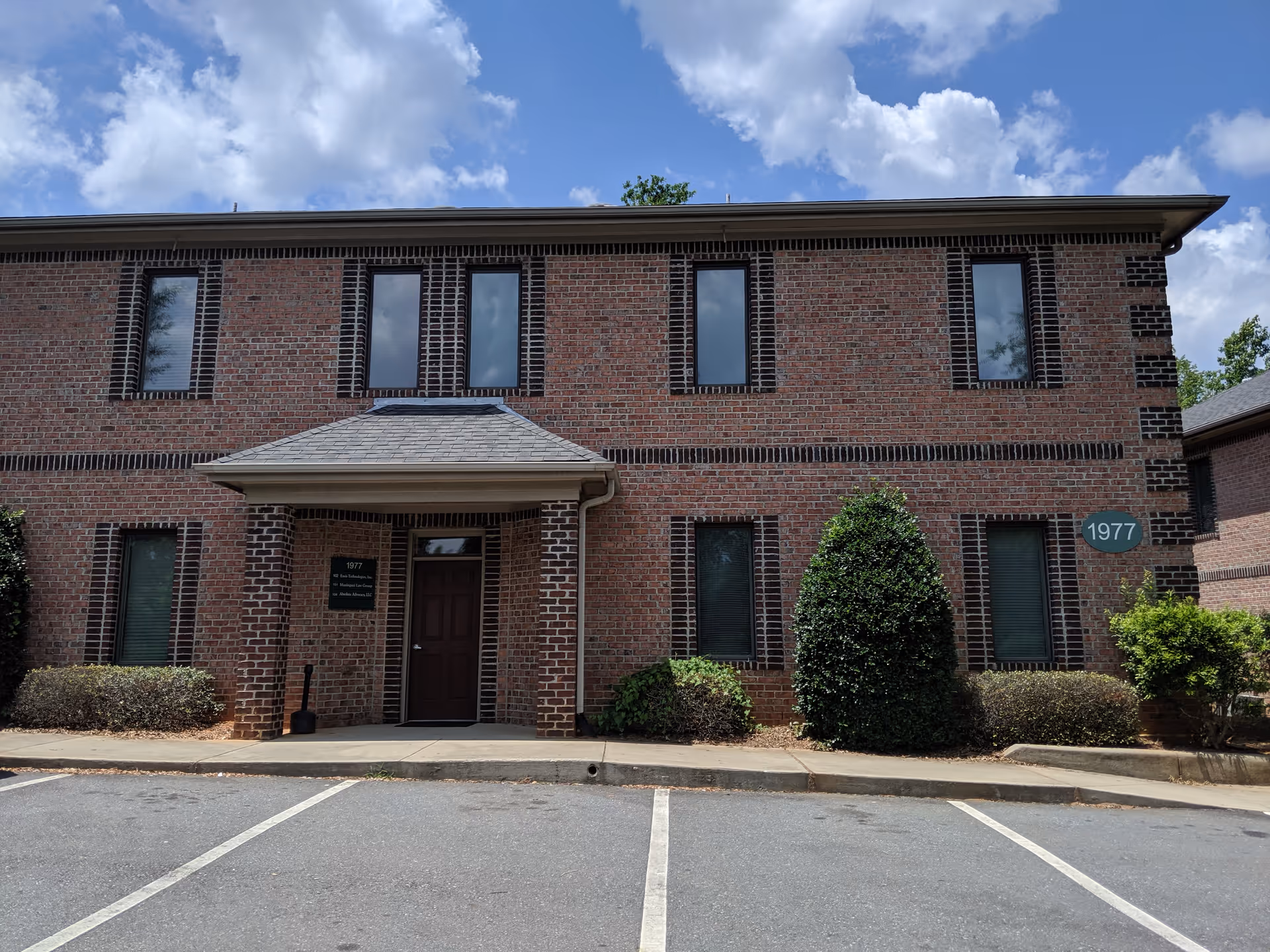 Brick two-story senior living building with entrance, landscaping, and a parking lot.